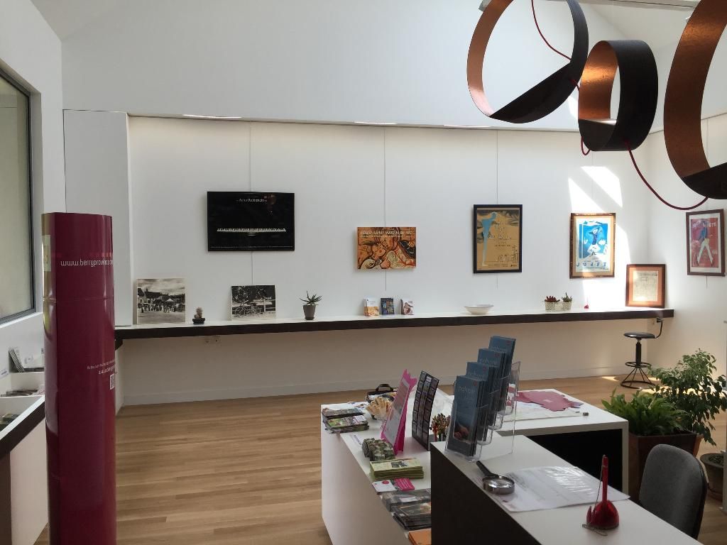 Intérieur avec des tableaux sur une longue étagère, un comptoir d'accueil, un éclairage moderne et un parquet.