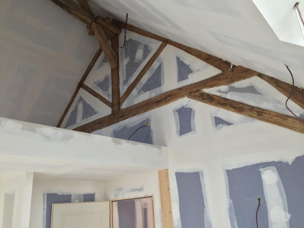 Vue intérieure d'une pièce sous combles avec poutres apparentes.