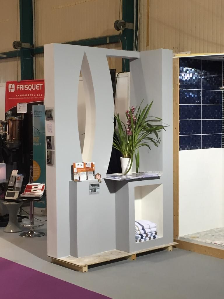 Présentoir gris avec plante et serviettes, faisant partie d'un stand d'exposition, sur palettes en bois.