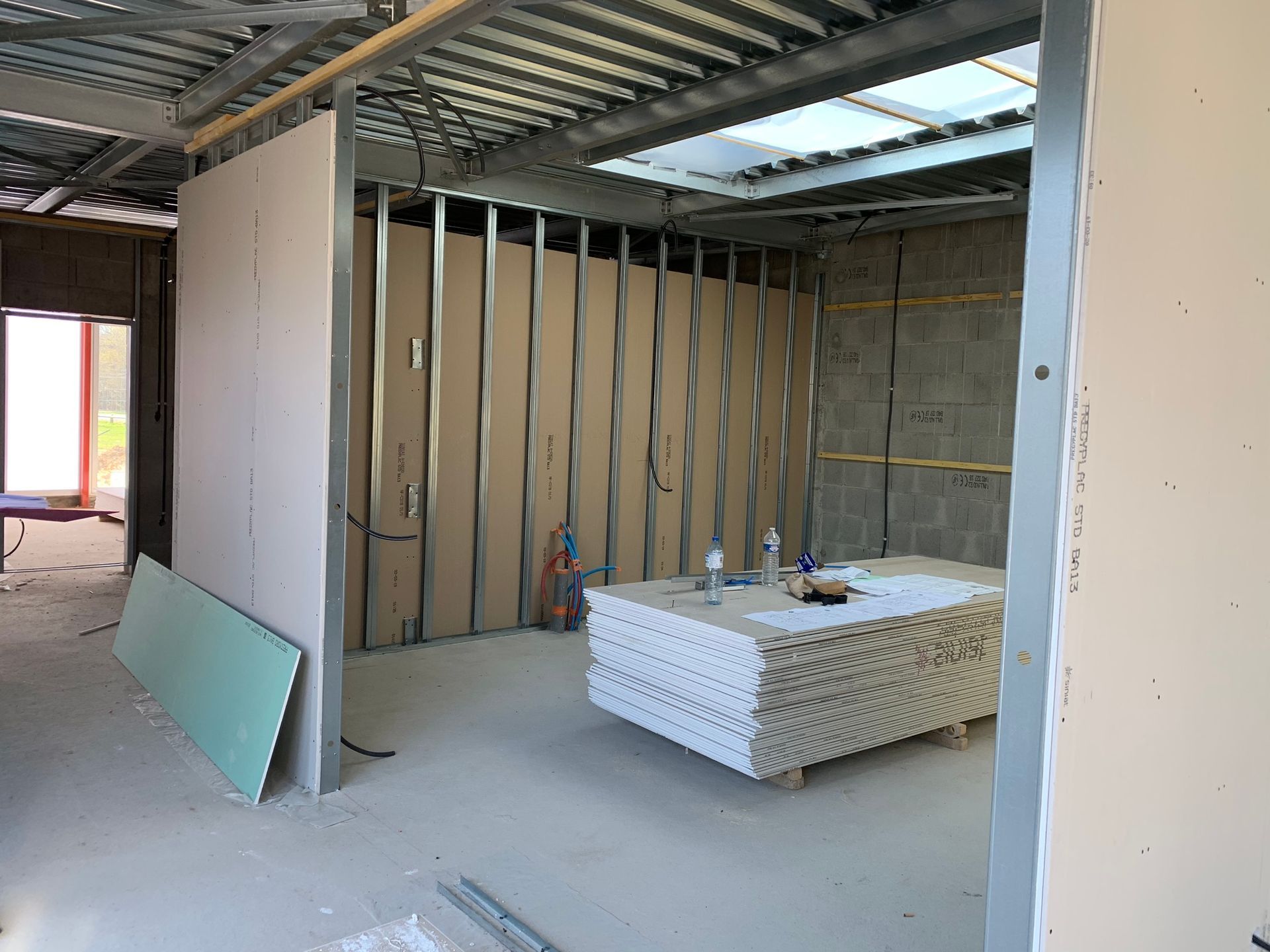 Aménagement intérieur : ossature métallique et plaques de plâtre, pièce aux murs non finis.
