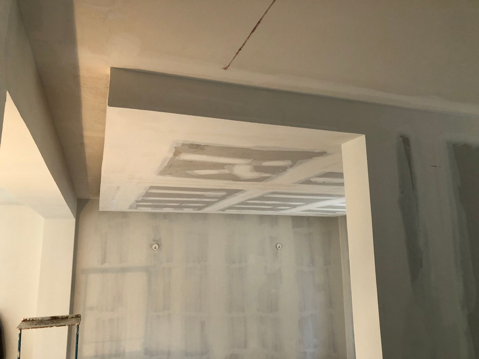 Vue intérieure d'une pièce en construction avec des cloisons sèches apparentes et un plafond en retrait.