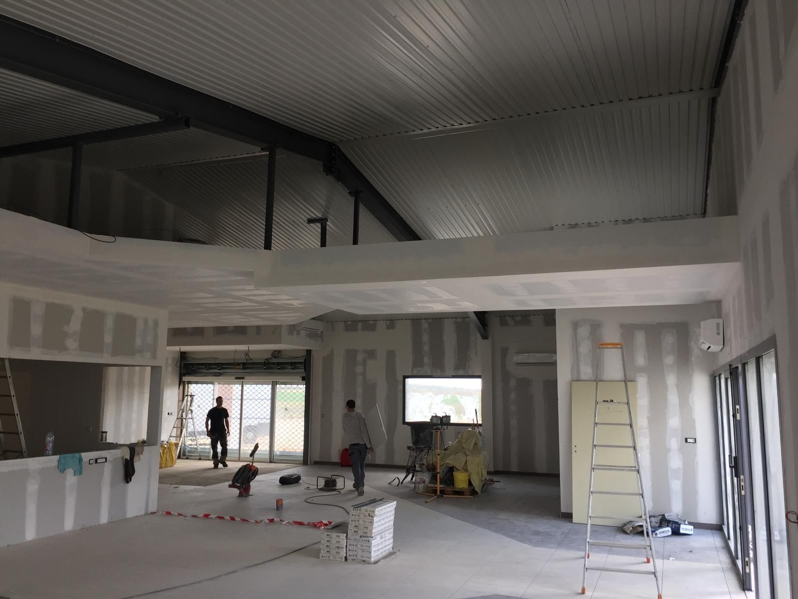 Vue intérieure d'un bâtiment en construction. Deux ouvriers sont visibles.