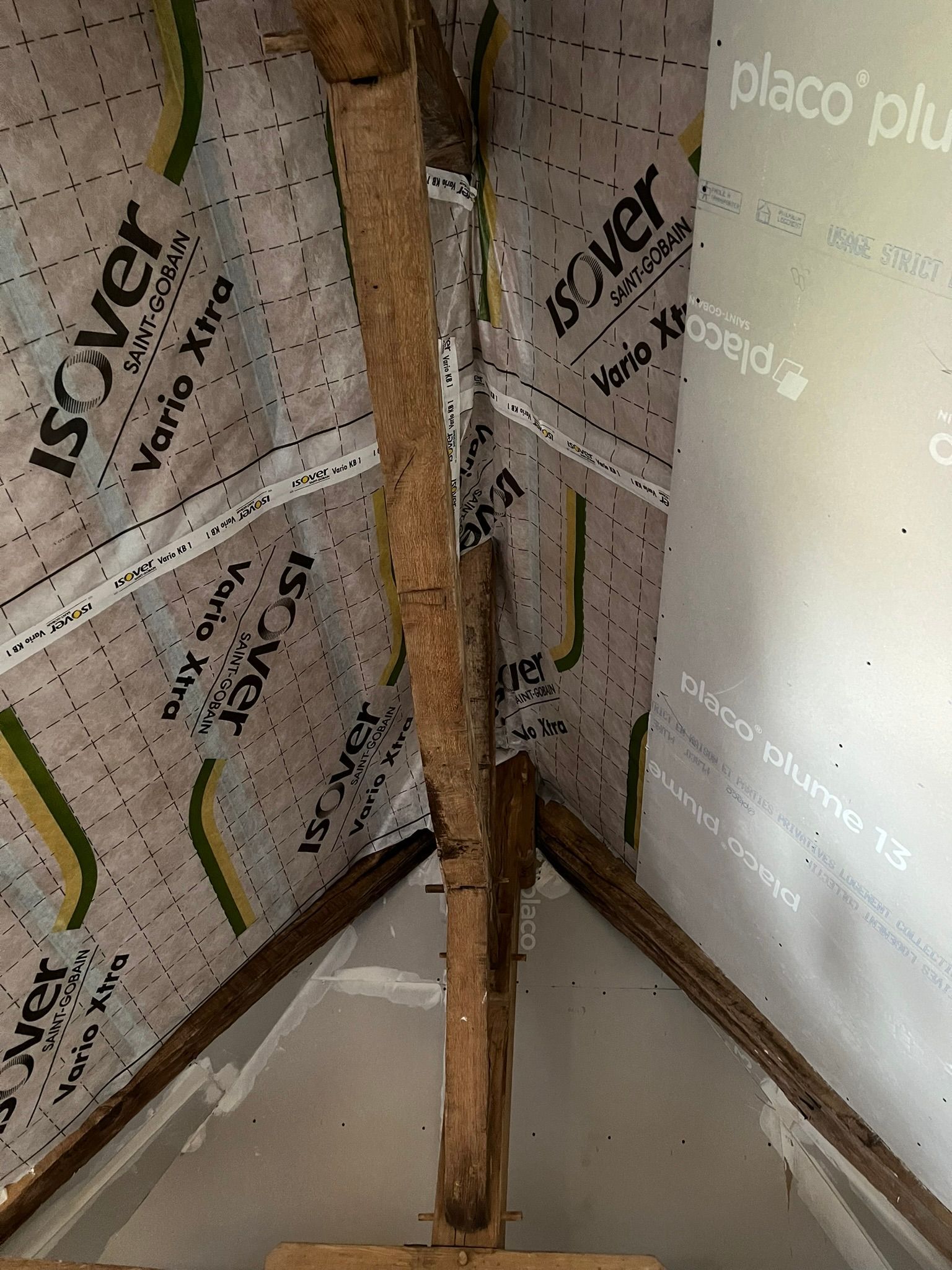 Poutres de toit en bois et isolation avec pare-vapeur installées.