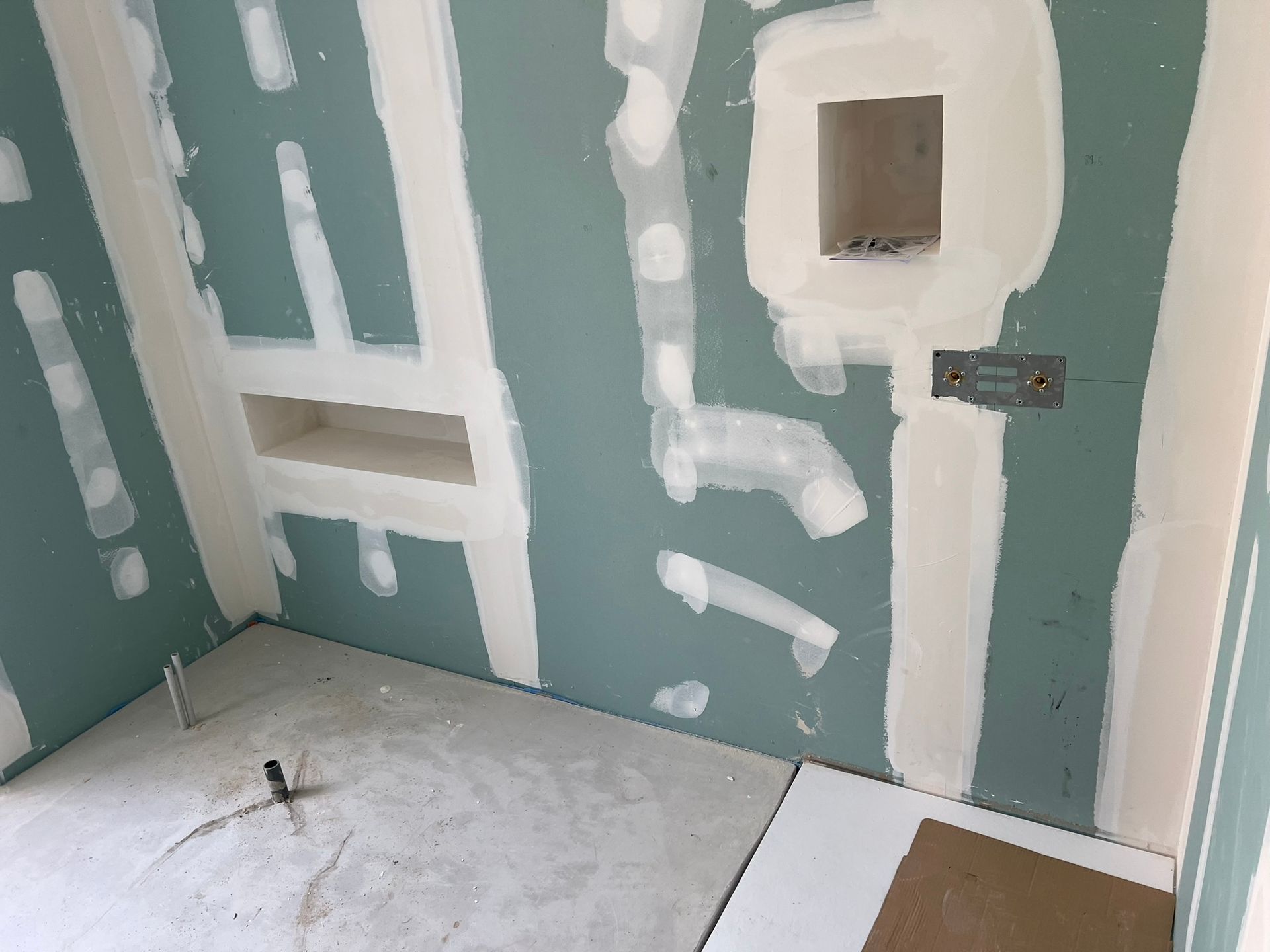 Mur intérieur en construction avec plaques de plâtre et enduit inachevé, bleu clair et blanc.