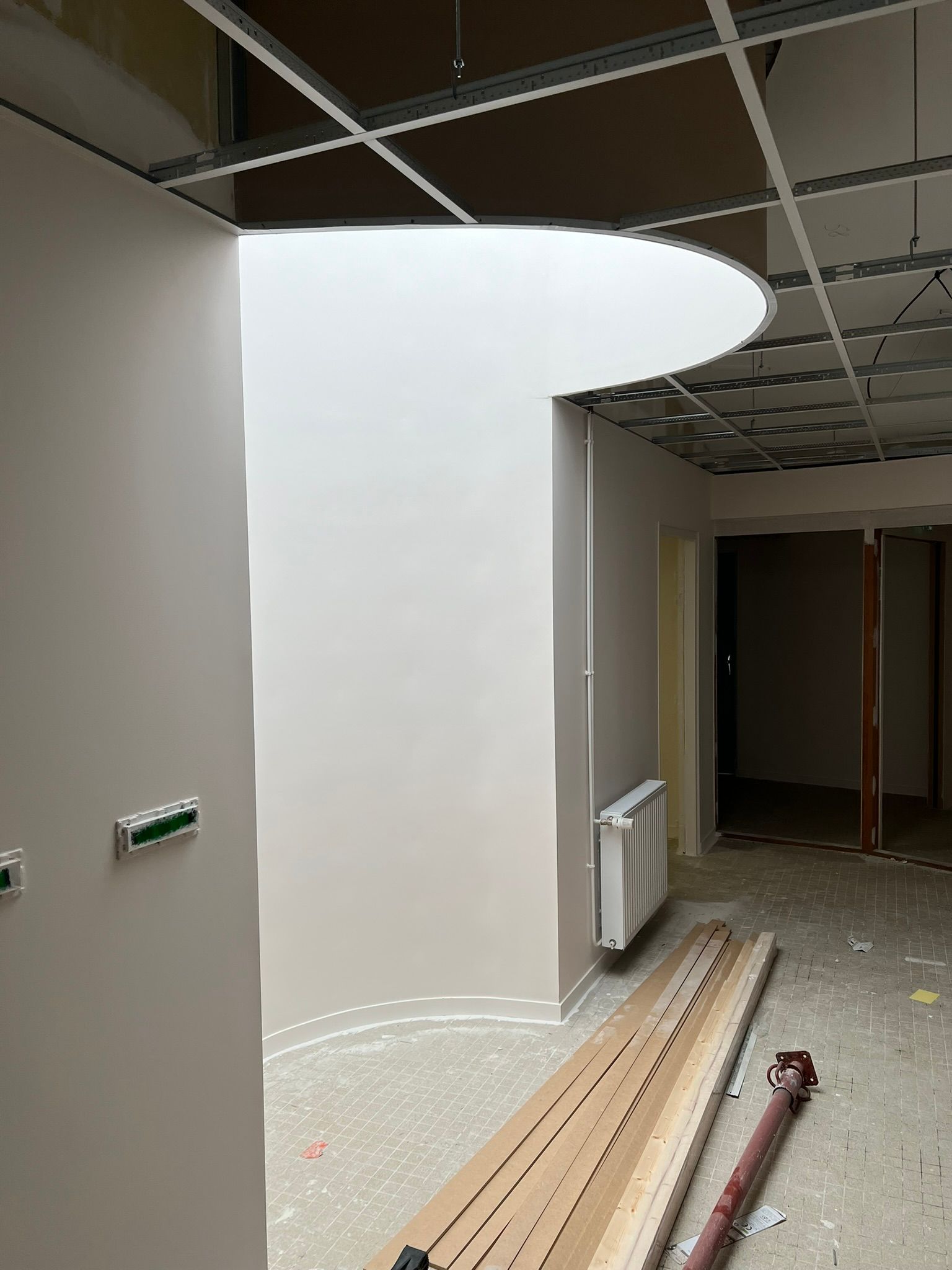 Couloir en construction avec une ouverture incurvée dans le mur et un faux plafond.