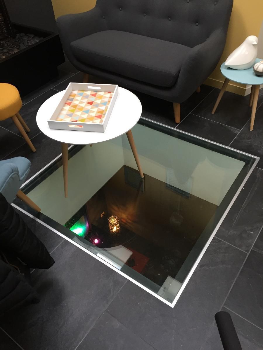 Un plancher de verre laisse entrevoir une pièce en dessous.
