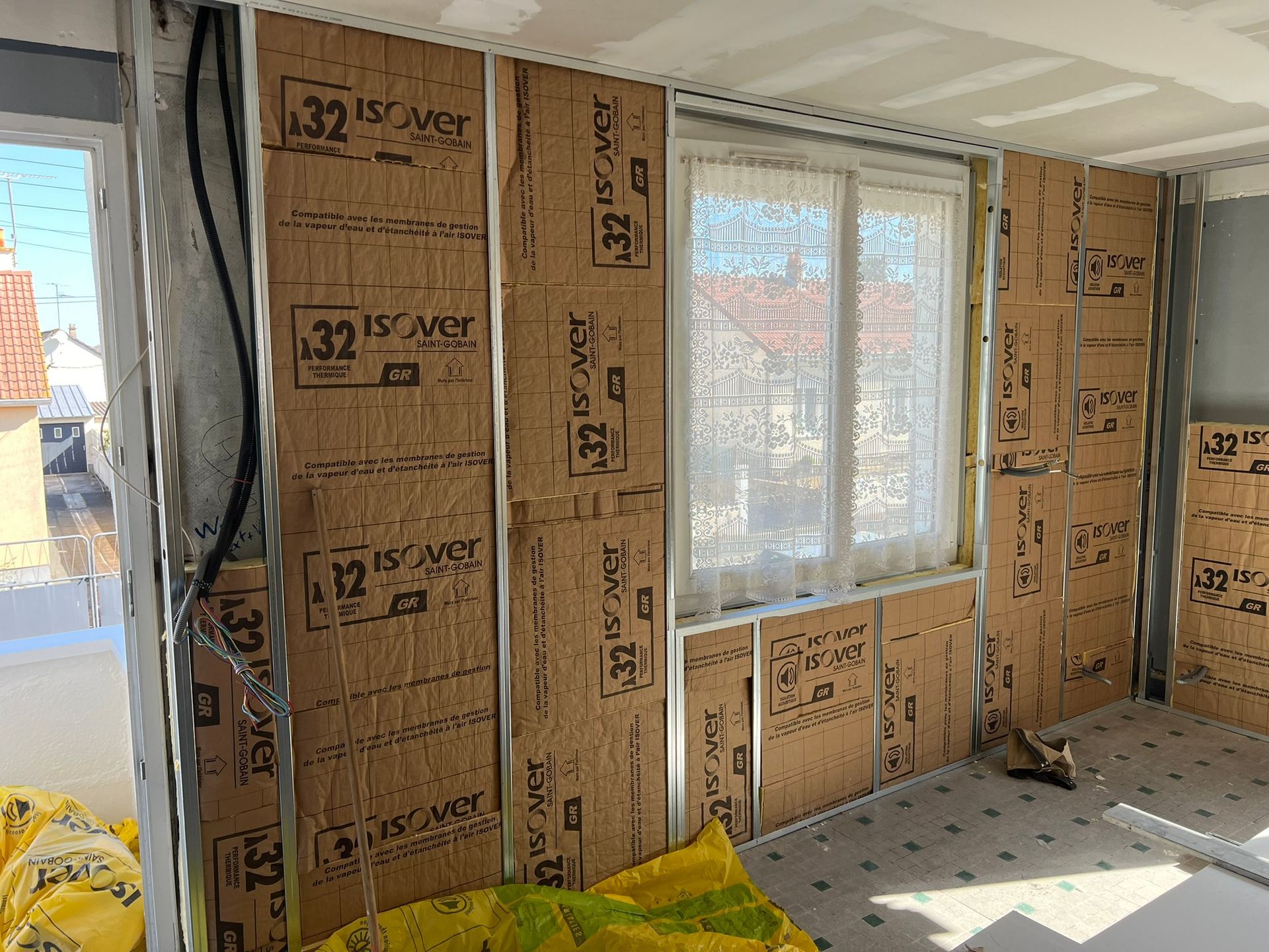 Aménagement intérieur d'une pièce ; murs avec panneaux isolants ; fenêtre ; ossature métallique ; matériaux de construction.