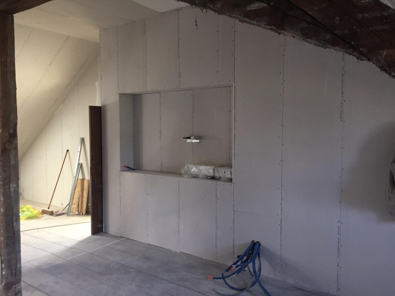 Vue intérieure d'une pièce dont les murs sont recouverts de plaques de plâtre, avec une niche.