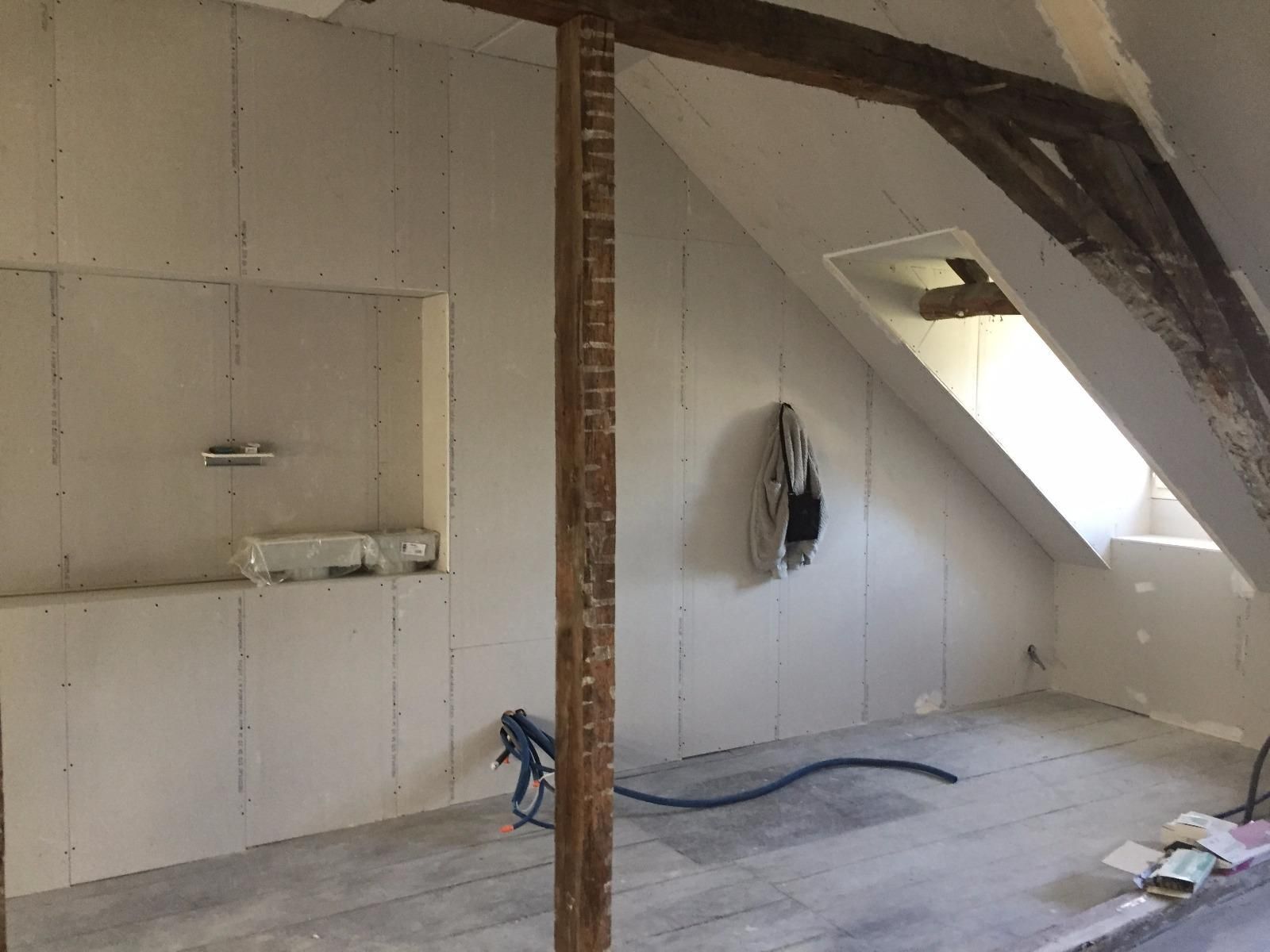 Aménagement d'une pièce sous les combles avec cloisons sèches et poutres apparentes.