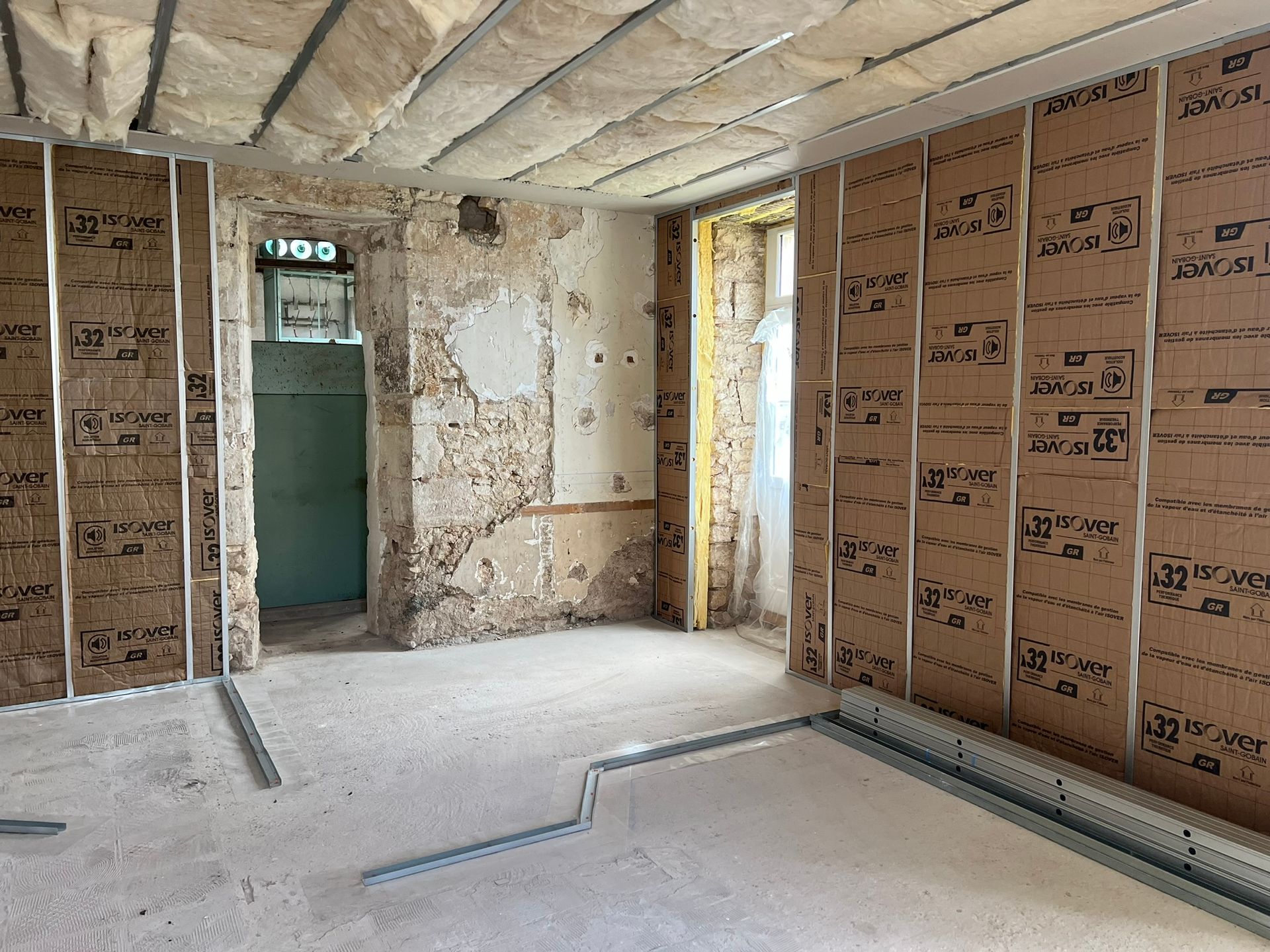 Pièce en rénovation avec isolation et ossature apparentes sur les murs et le plafond.