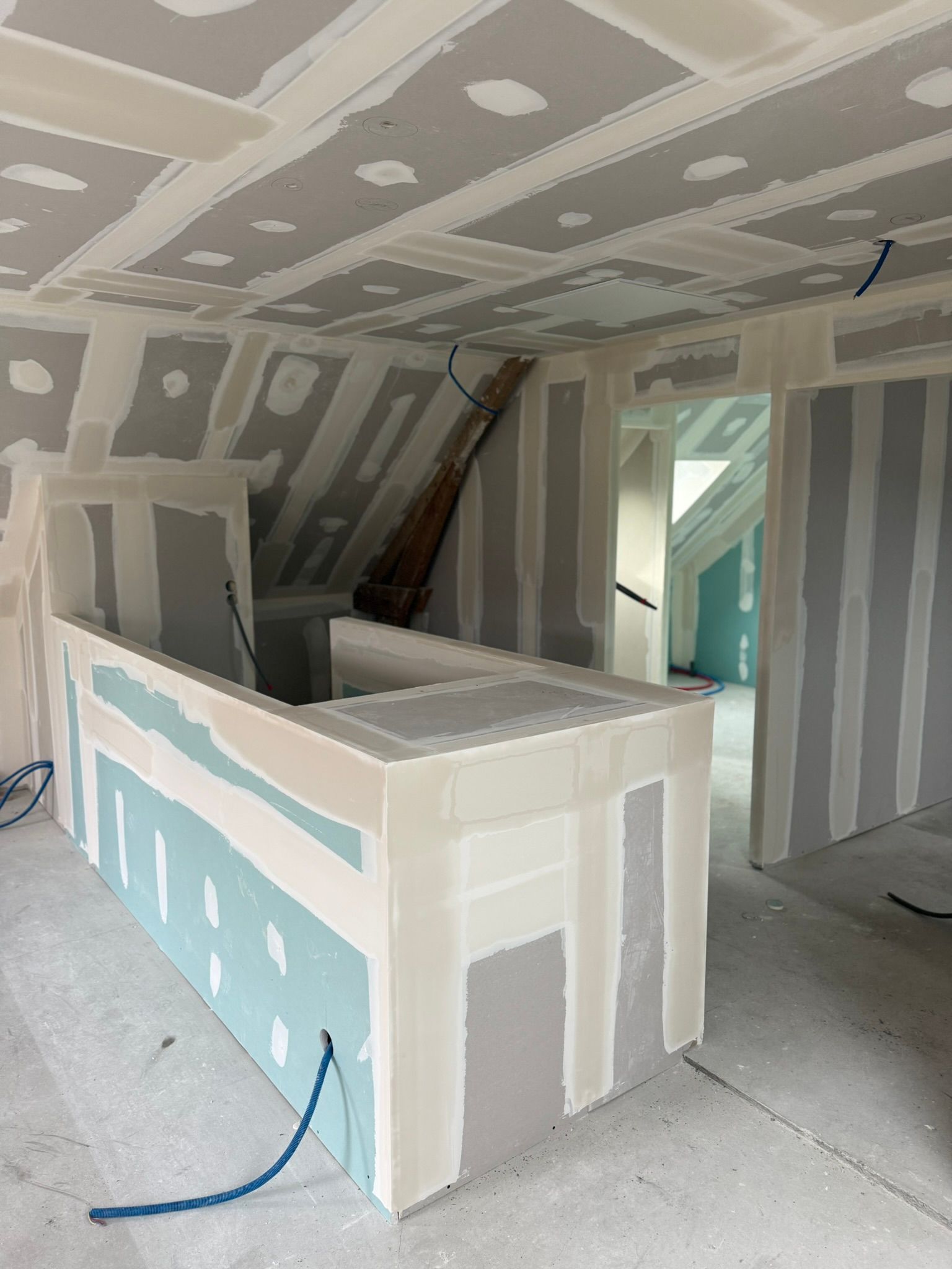 Intérieur en travaux, murs et plafond recouverts de plaques de plâtre, pièce communiquant avec une autre pièce.