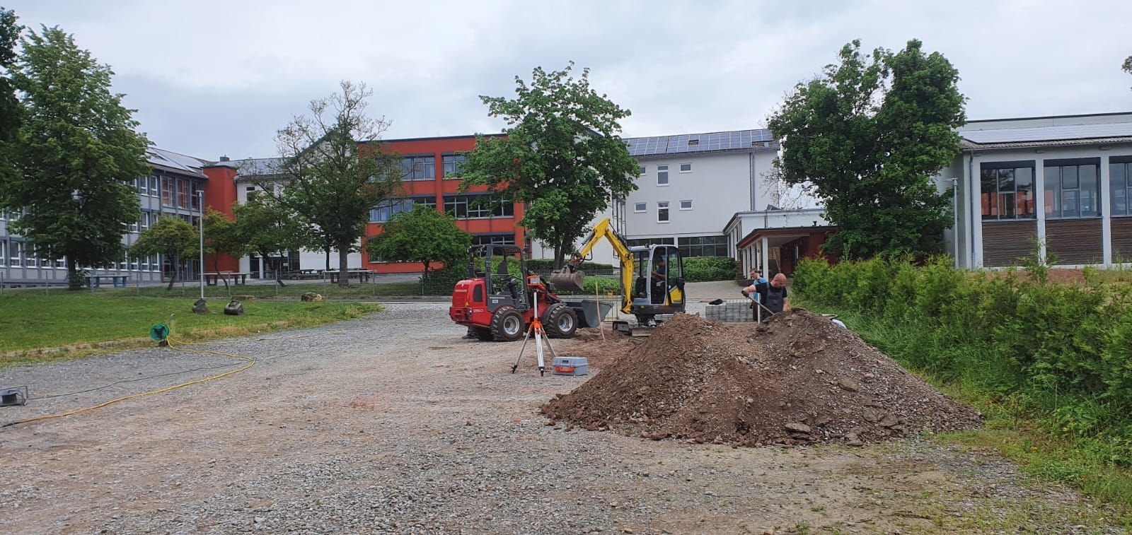Eine Baustelle mit einem Erdhaufen und einem Gebäude im Hintergrund.