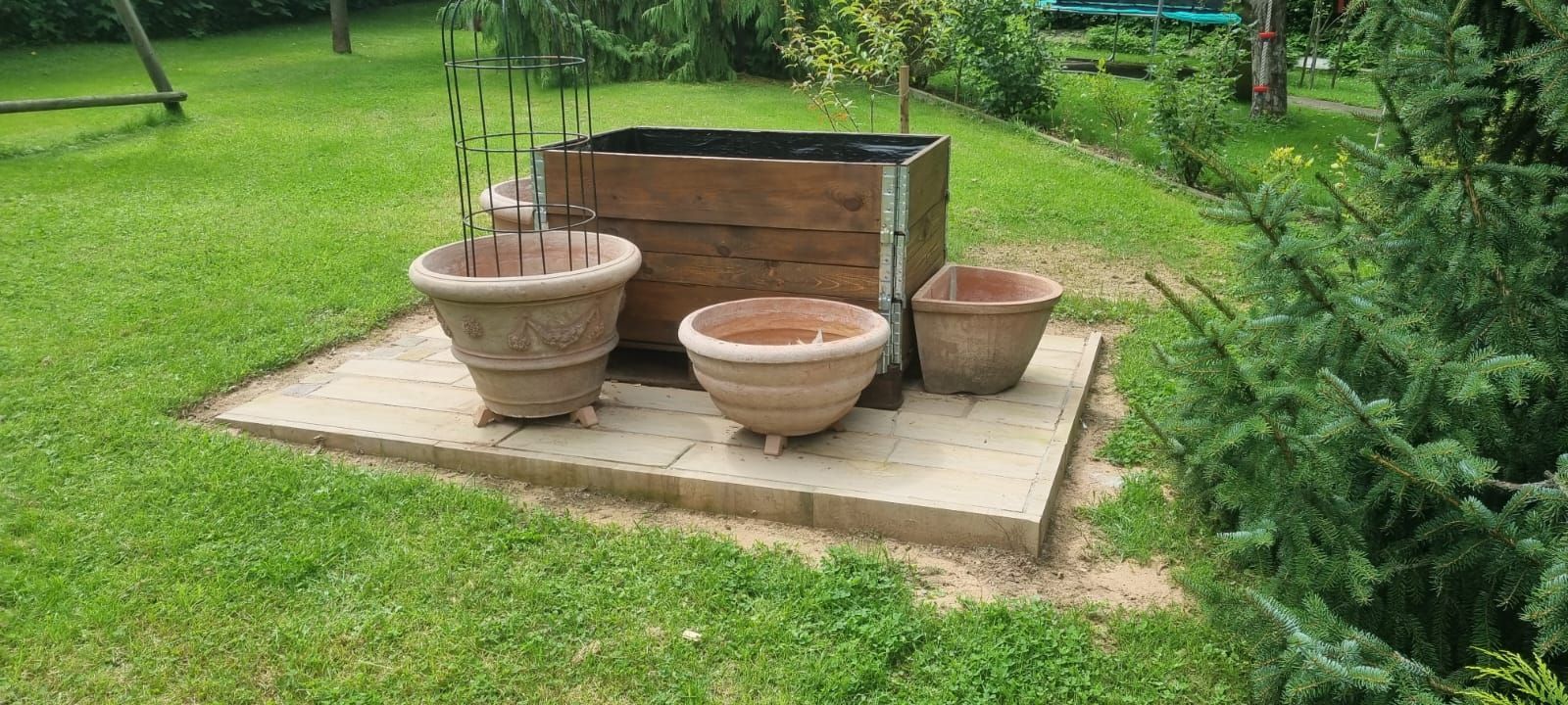 Eine Gruppe von Töpfen, die auf einer Betonplattform in einem Garten stehen.