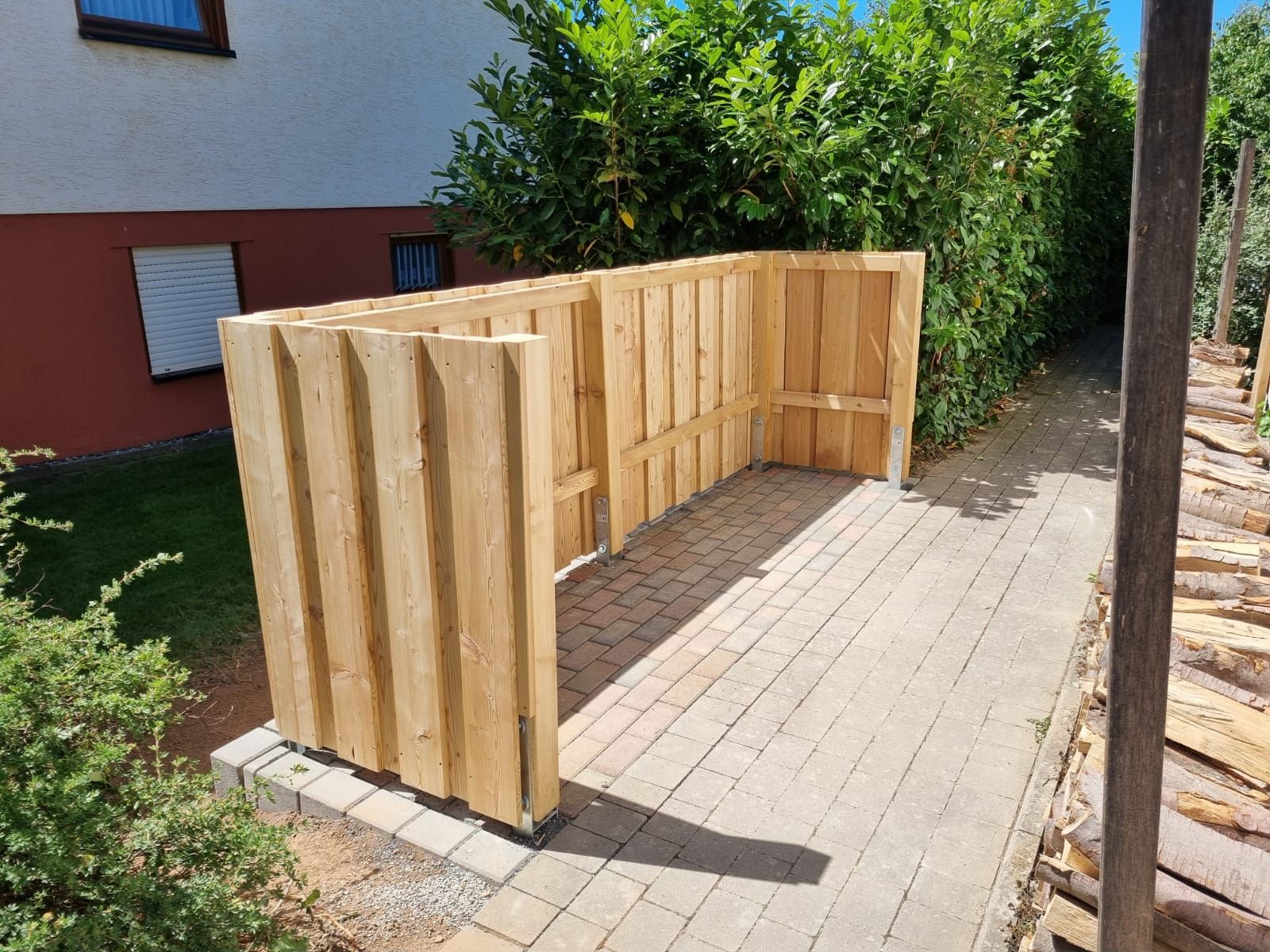 Auf einem Gehweg vor einem Haus steht ein Holzzaun.