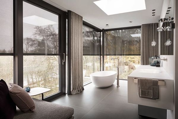 Ein Badezimmer mit Badewanne, Waschbecken und großen Fenstern.