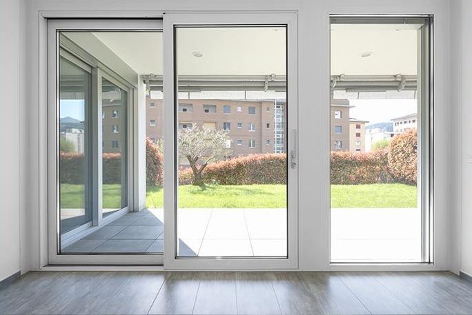 Ein leerer Raum mit Glasschiebetüren, die auf eine Terrasse führen.