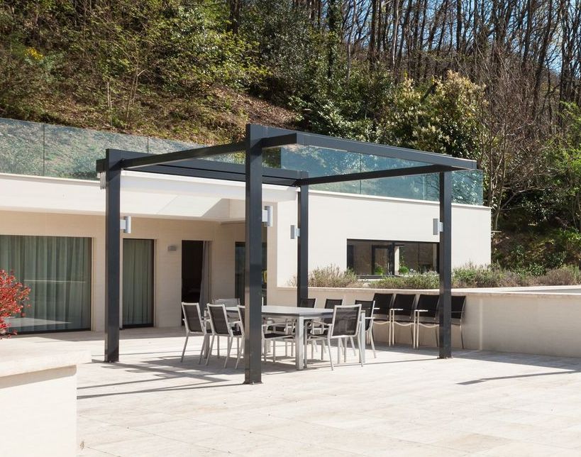 Eine Terrasse mit Tisch und Stühlen unter einer Pergola.