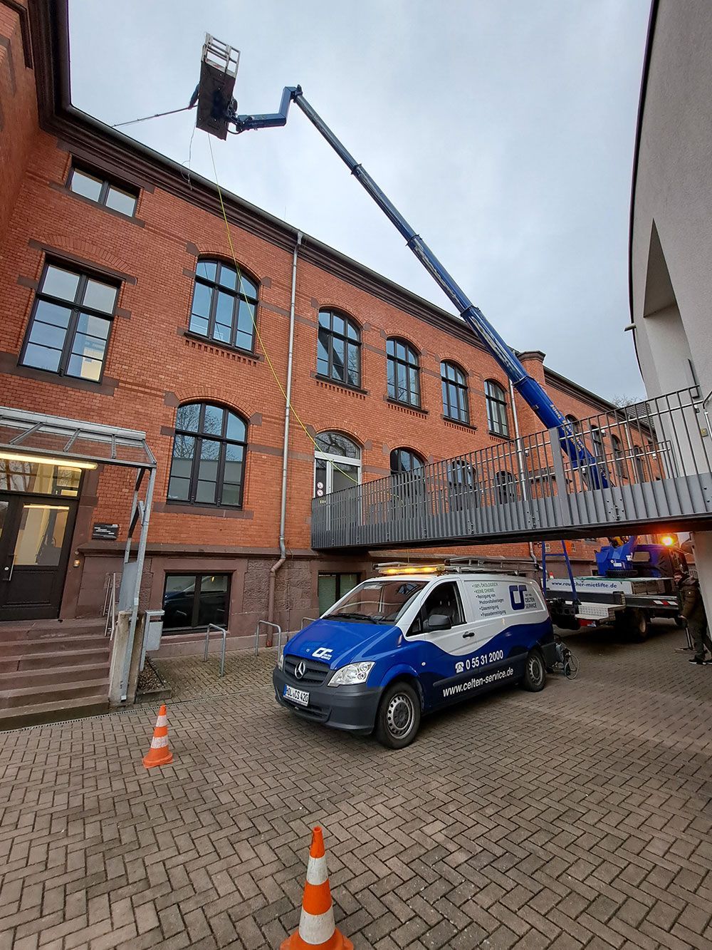 Ein blau-weißer Lieferwagen steht vor einem großen Backsteingebäude.