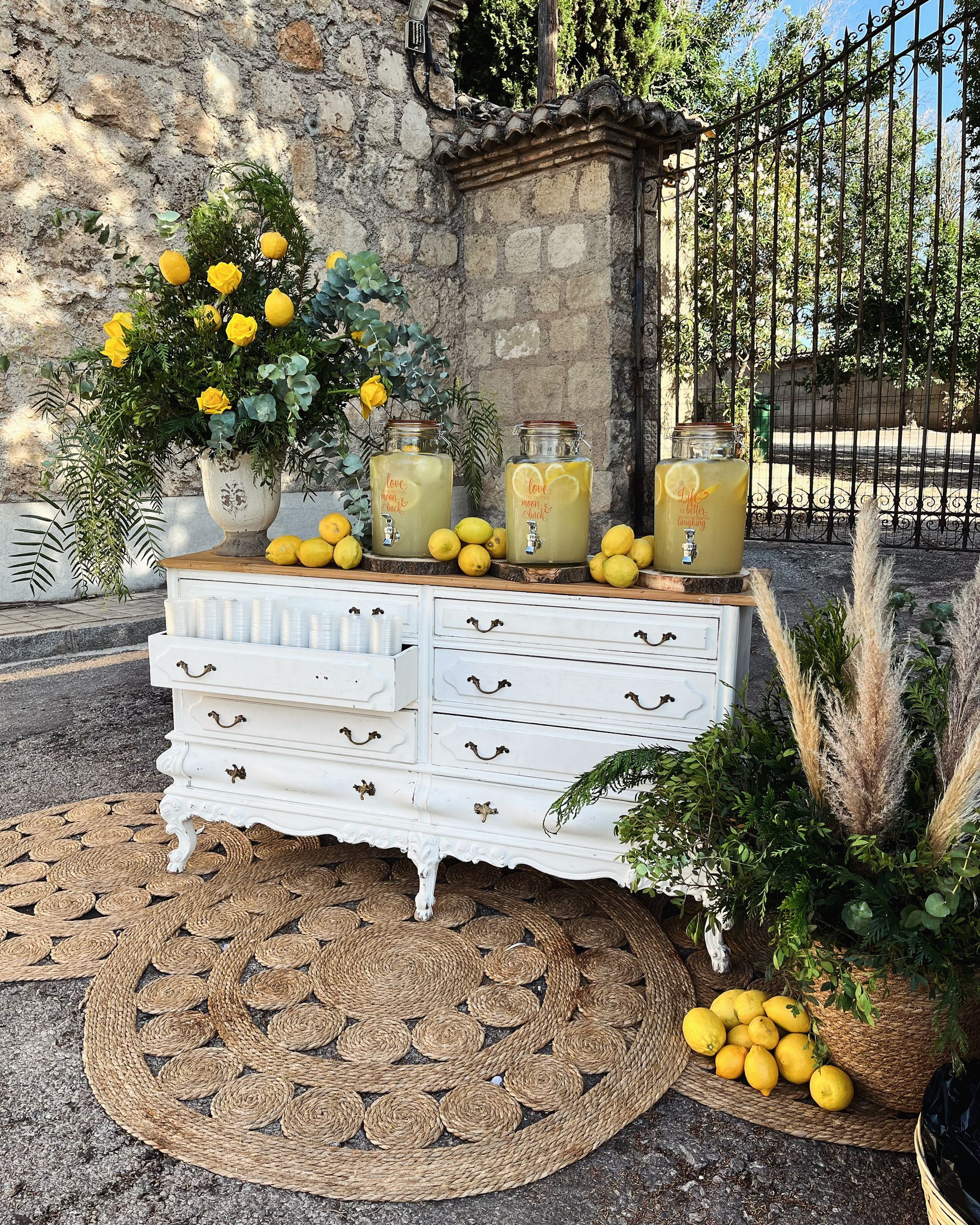 Una cómoda blanca está decorada con limones y flores para un puesto de limonada.