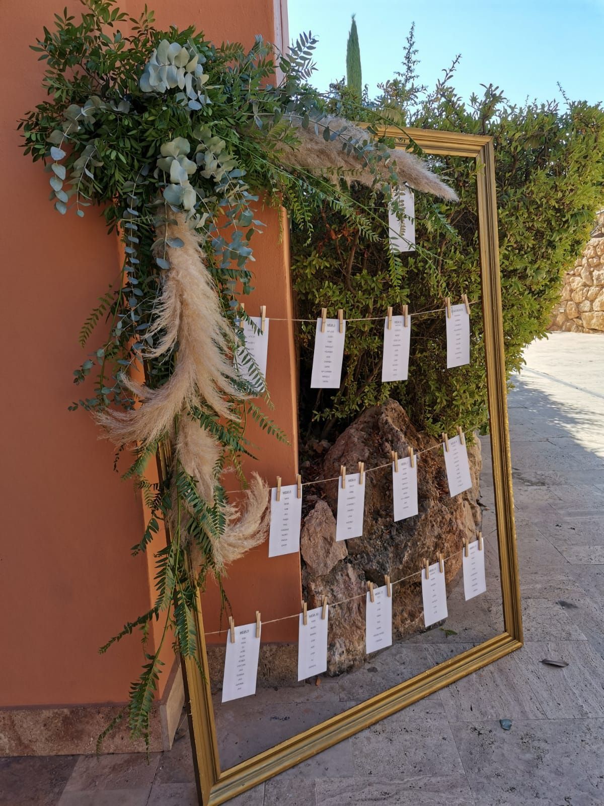 Un gran marco dorado con tarjetas de asientos colgando de él.