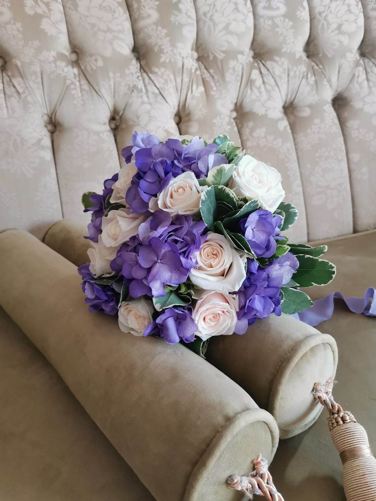 Un ramo de flores moradas y blancas está sobre un sofá.