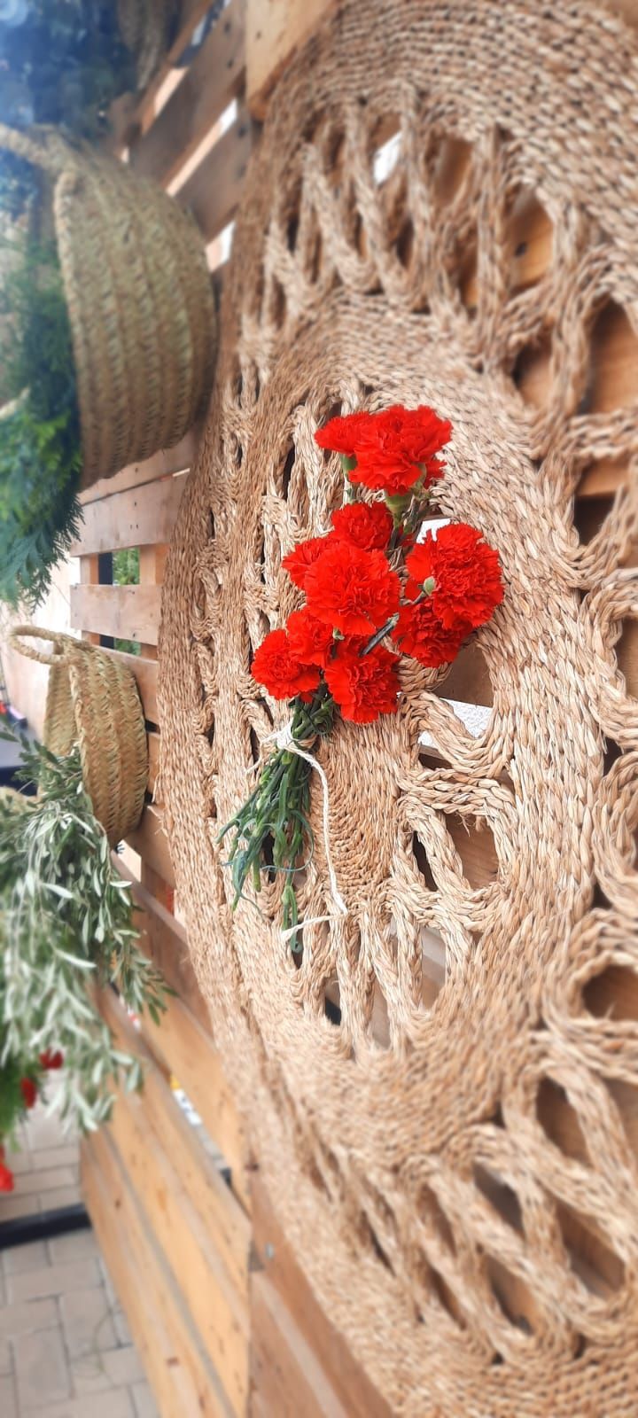Un ramo de flores rojas cuelga en una pared de madera.