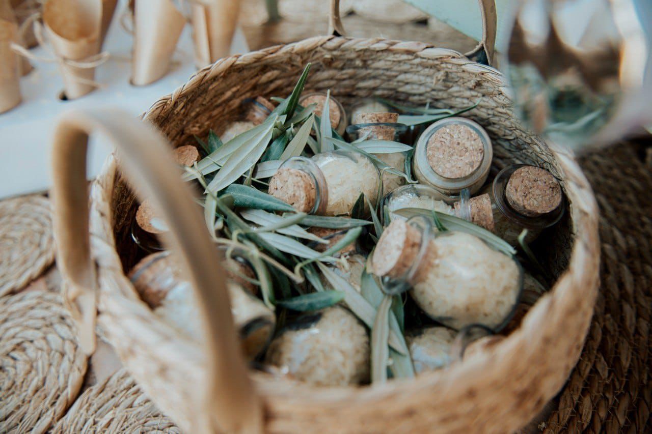 Una cesta de mimbre llena de frascos y hojas sobre una mesa.