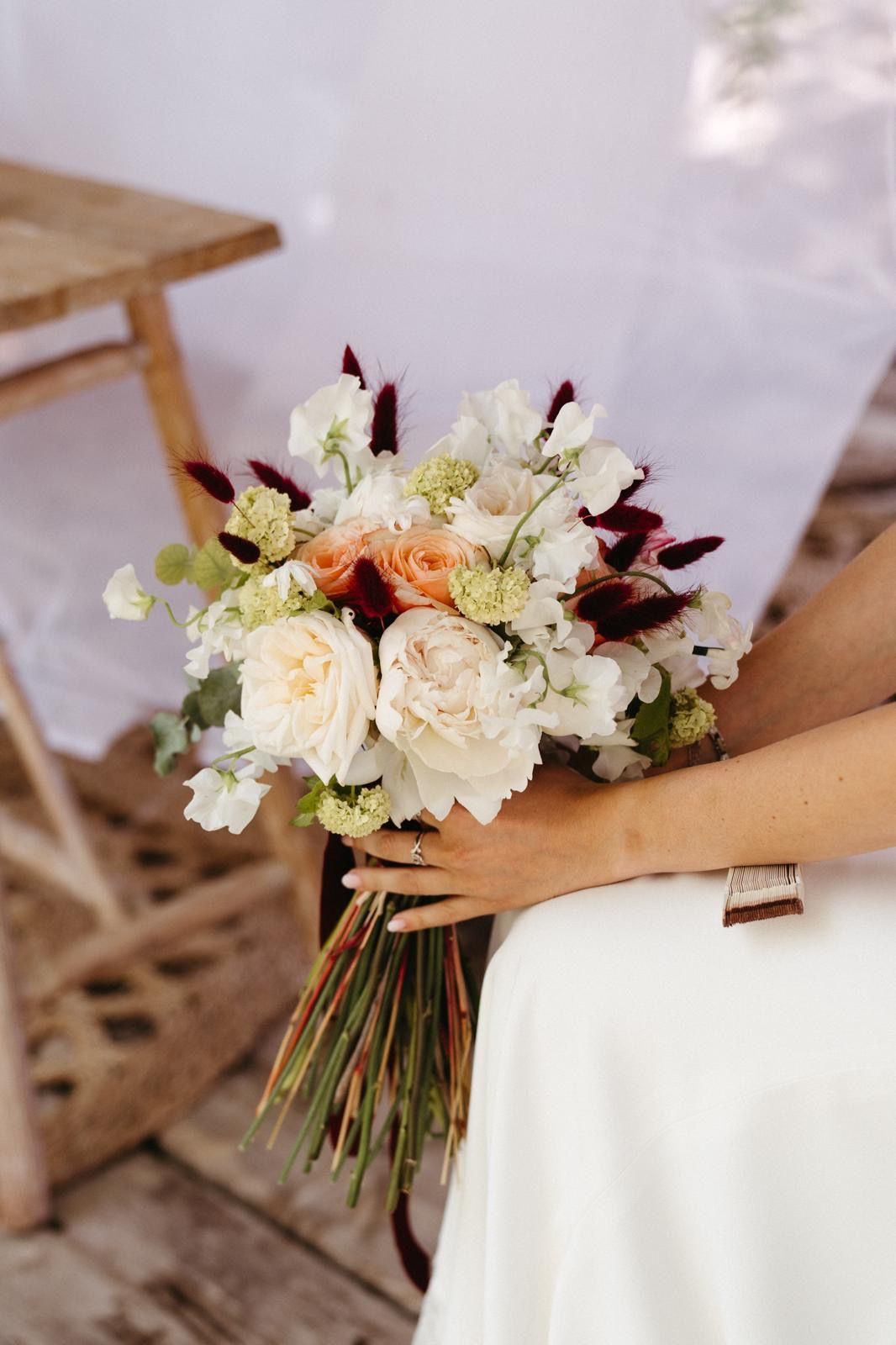 Una novia sostiene un ramo de flores en sus manos.