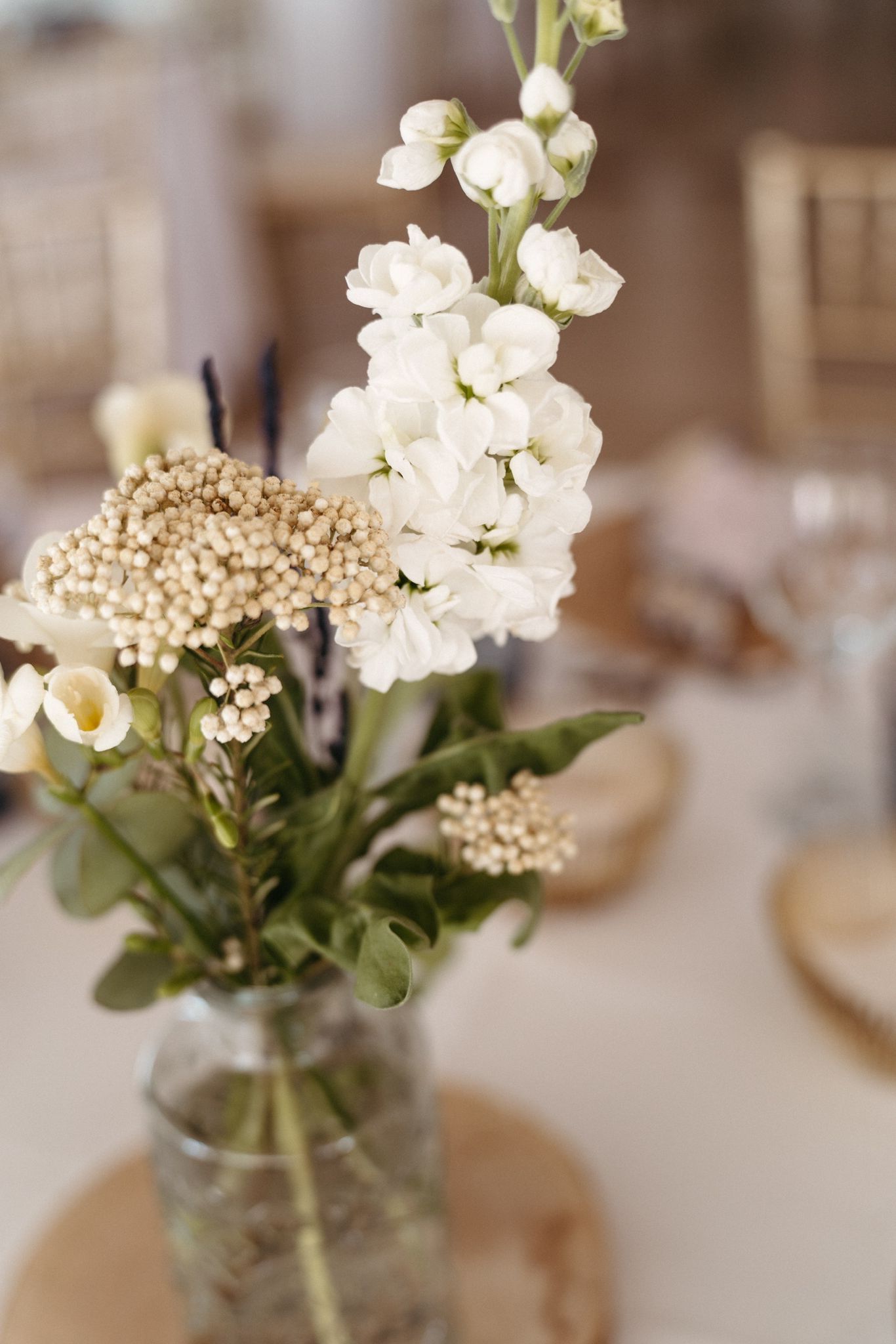 Un jarrón lleno de flores blancas está sobre una mesa.