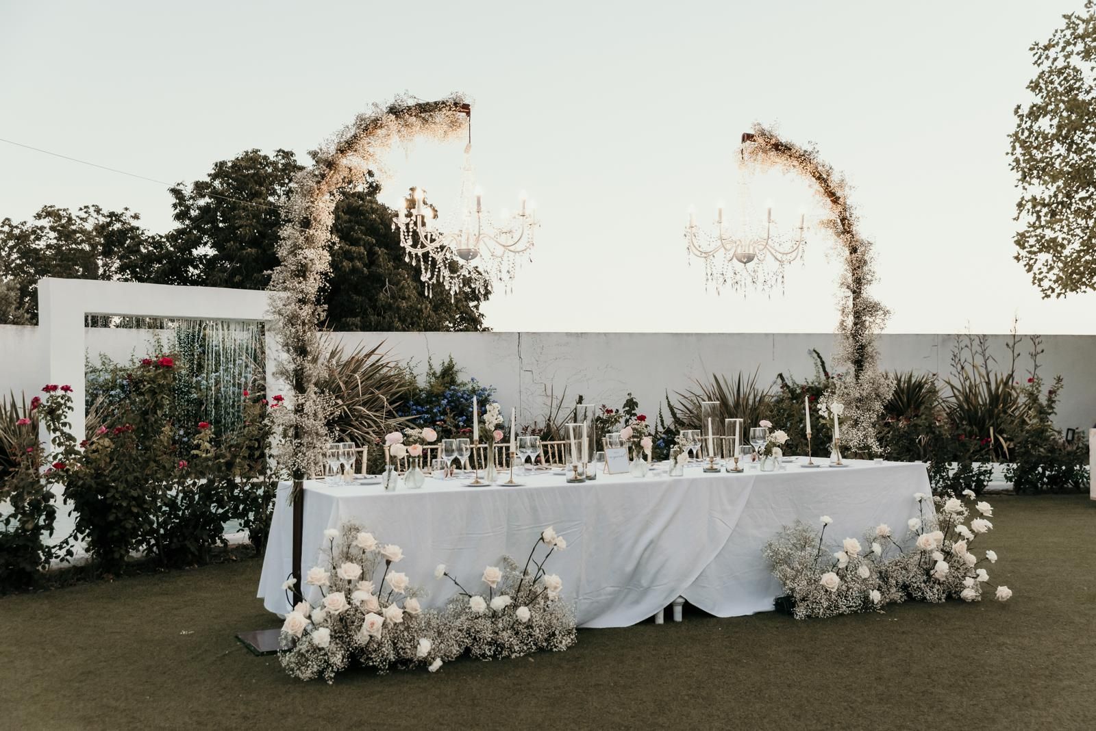 Una larga mesa blanca se encuentra sobre un exuberante campo verde.