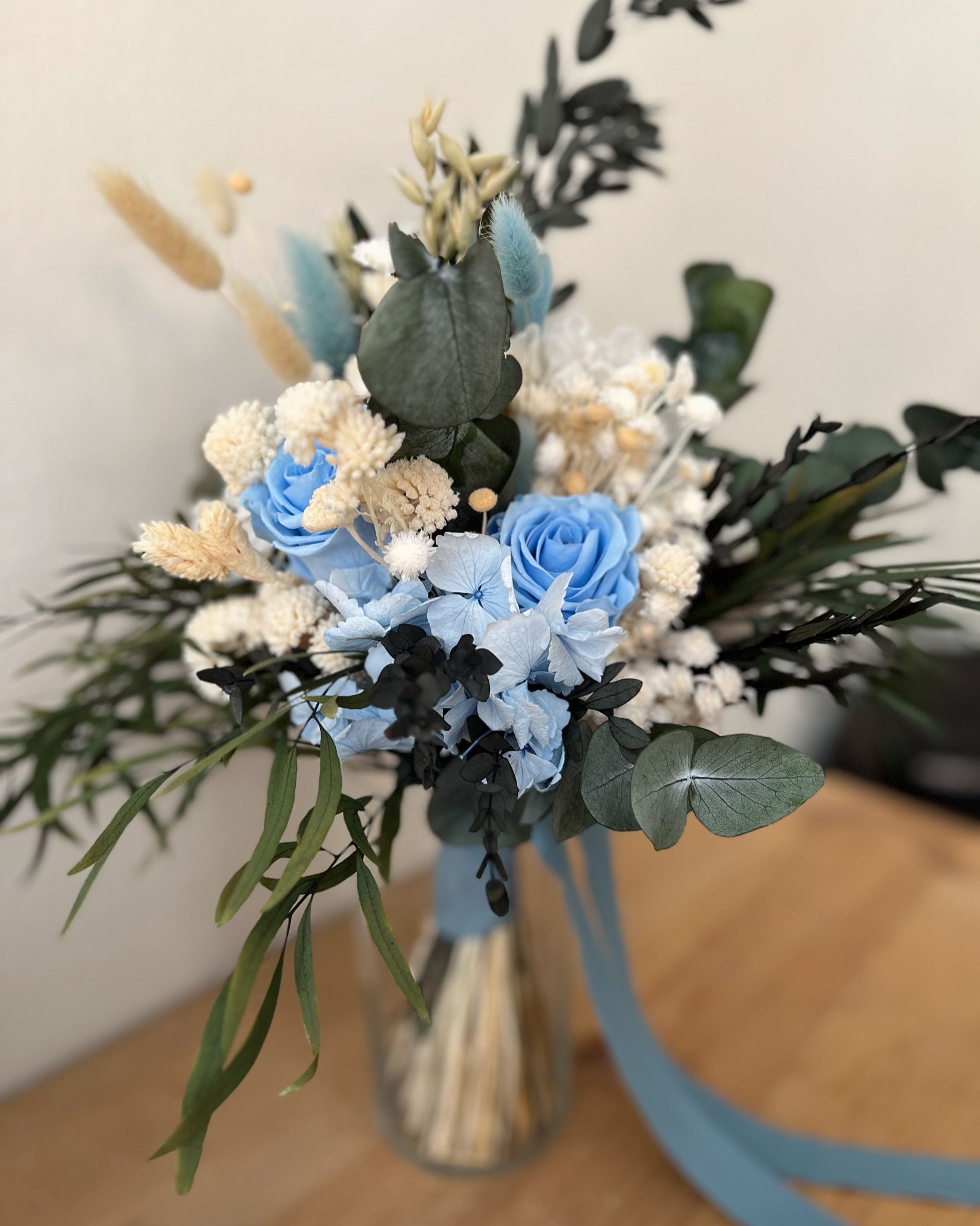Un ramo de flores azules y blancas en un jarrón sobre una mesa.