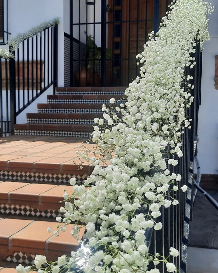 Una escalera decorada con flores blancas y velo de novia.