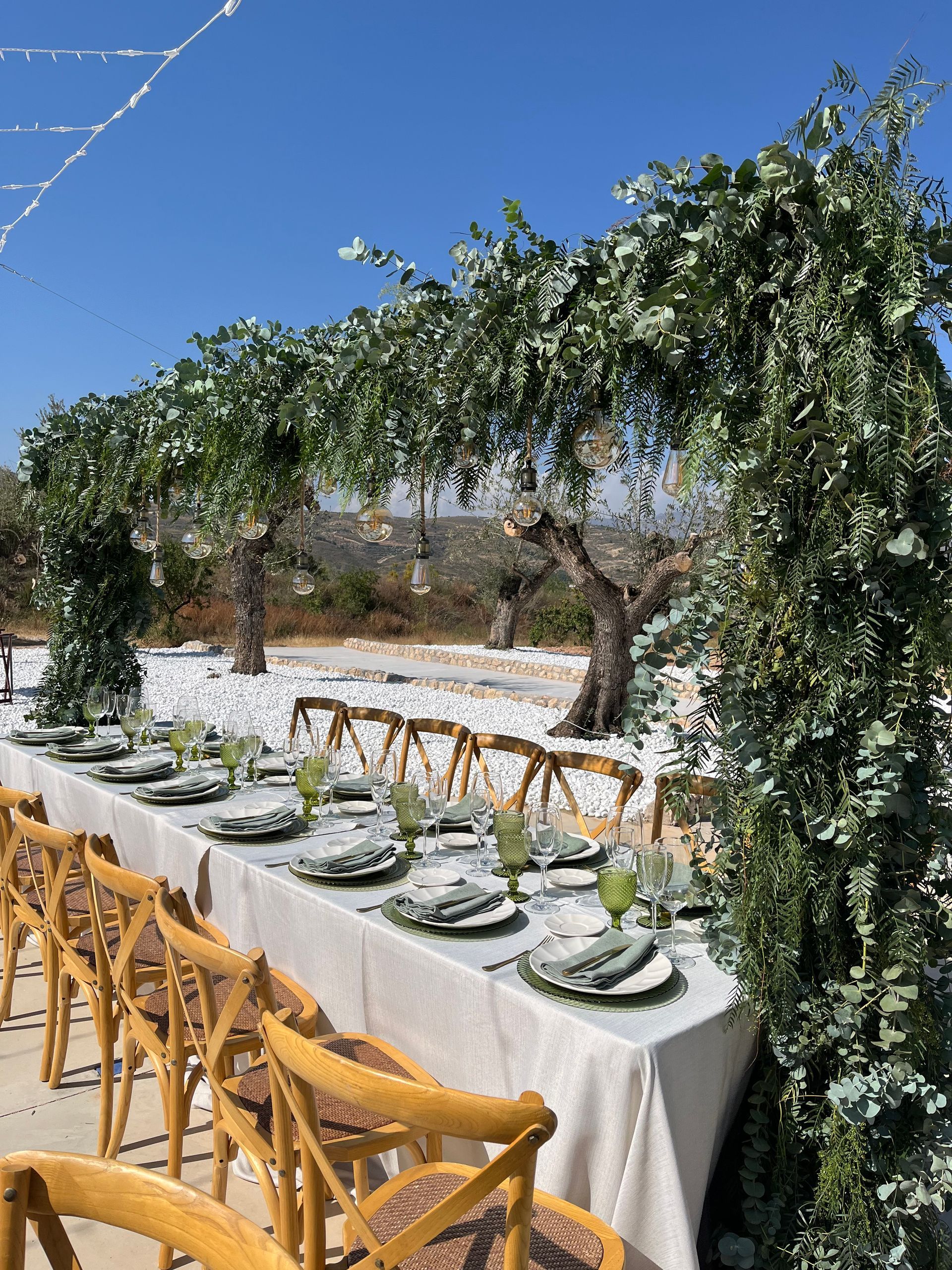 Una mesa larga con platos, vasos y sillas preparada para una recepción de boda.
