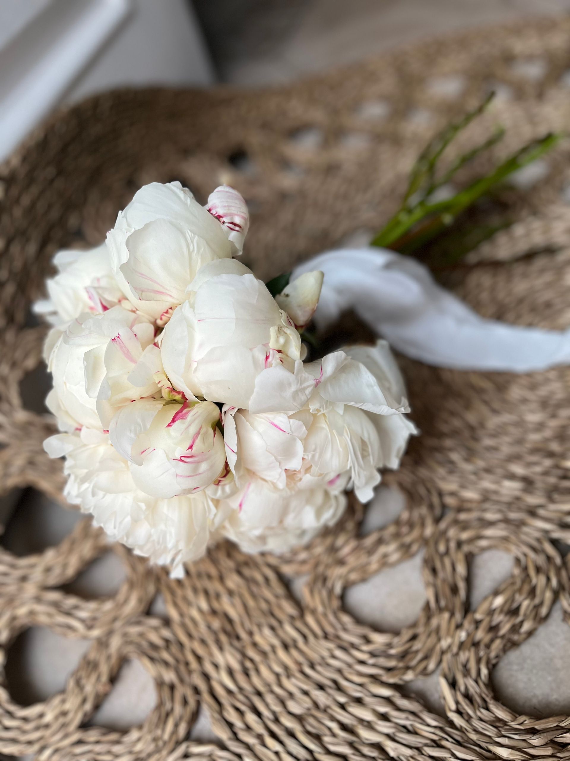 Un ramo de flores blancas reposa sobre una estera de mimbre.