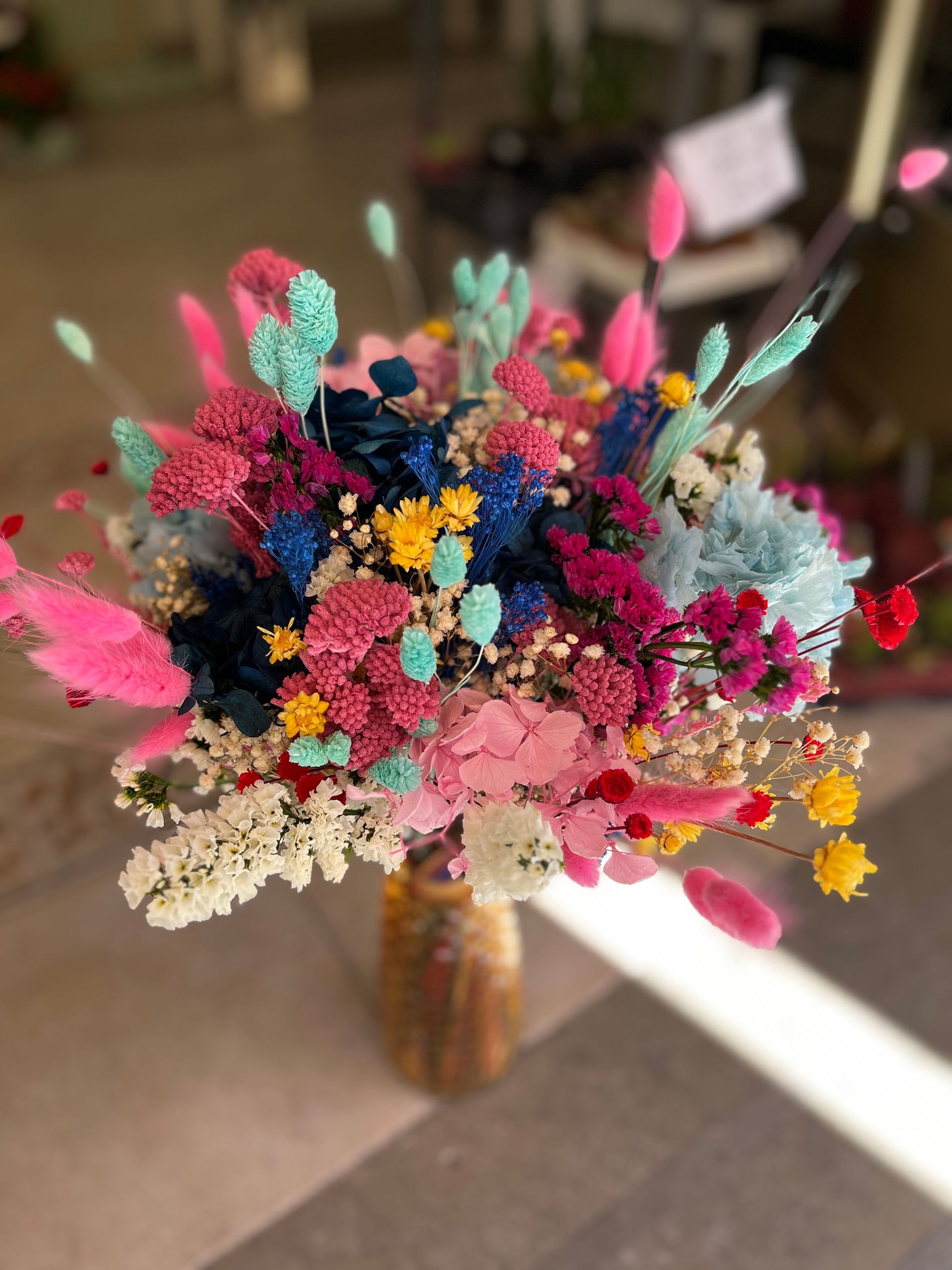 Un jarrón lleno de flores de colores está sobre una mesa.