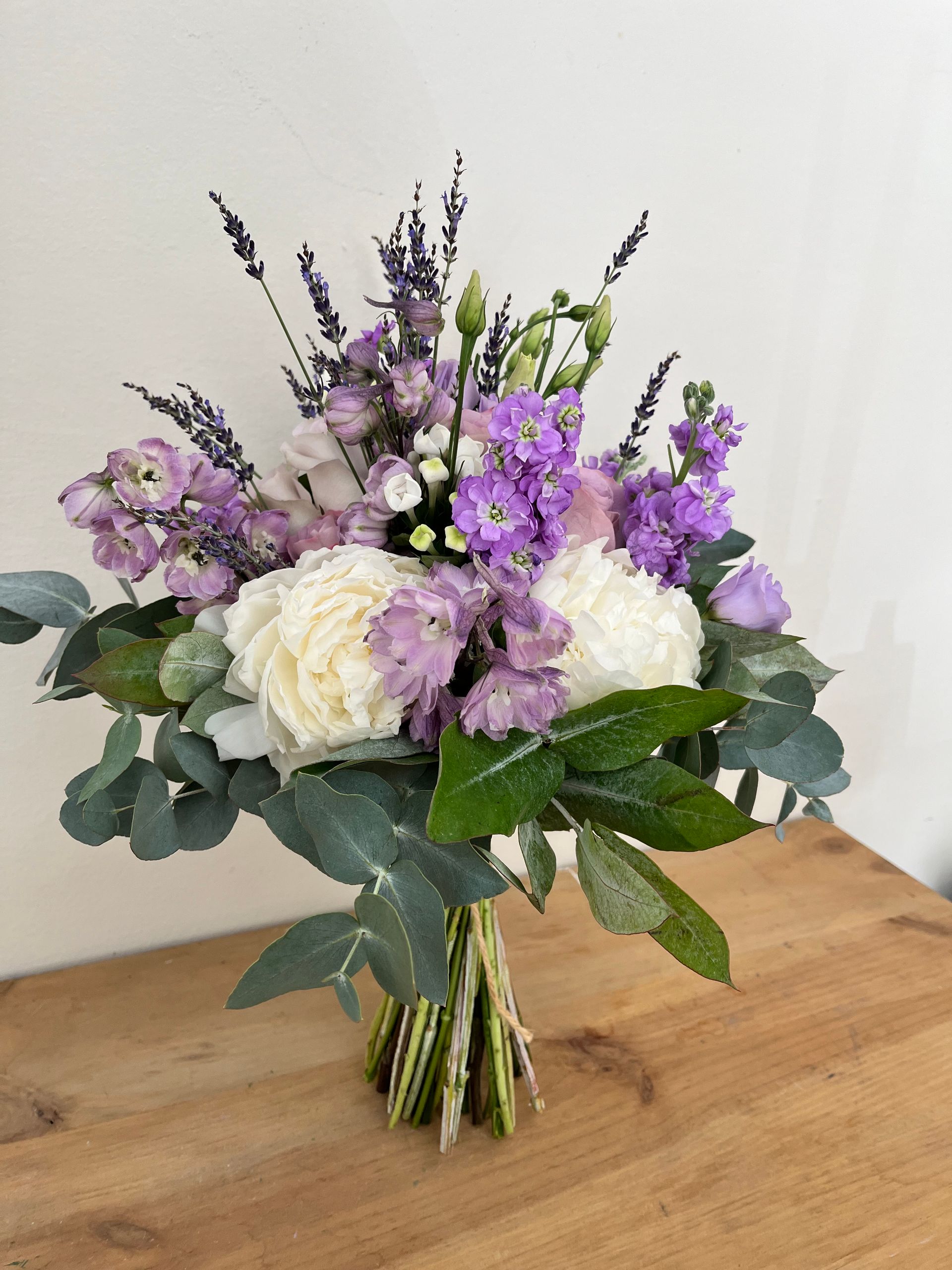 Un ramo de flores moradas y blancas está sobre una mesa de madera.