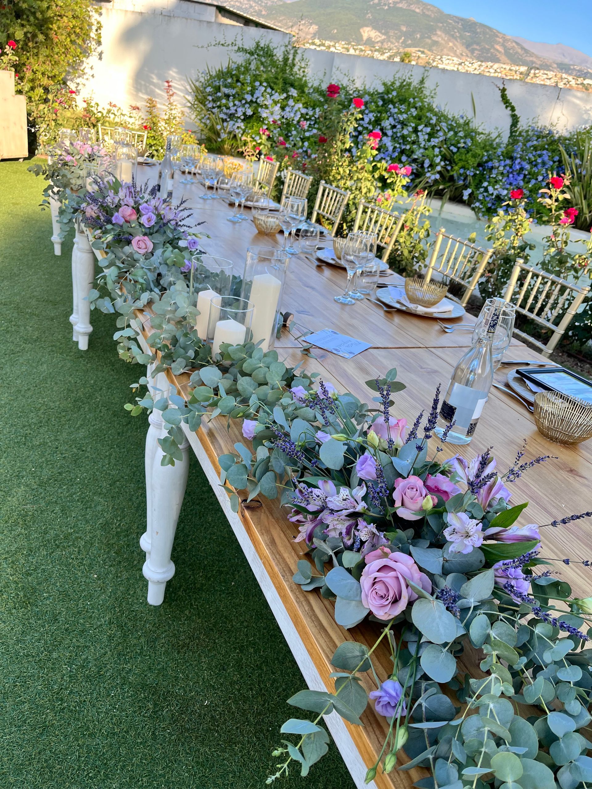 Una mesa larga de madera con flores y velas sobre ella.