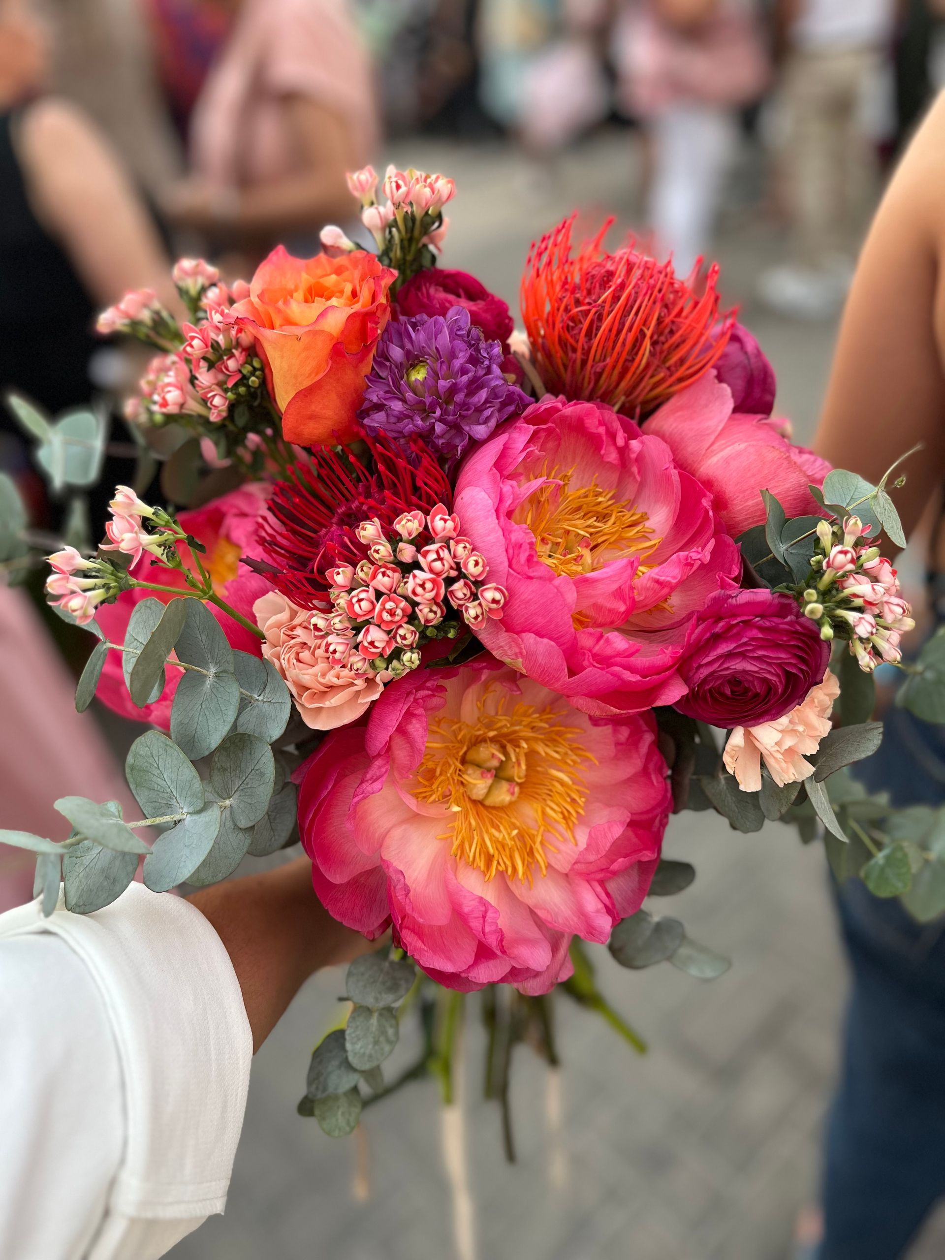 Una mujer sostiene un ramo de flores de colores en su mano.