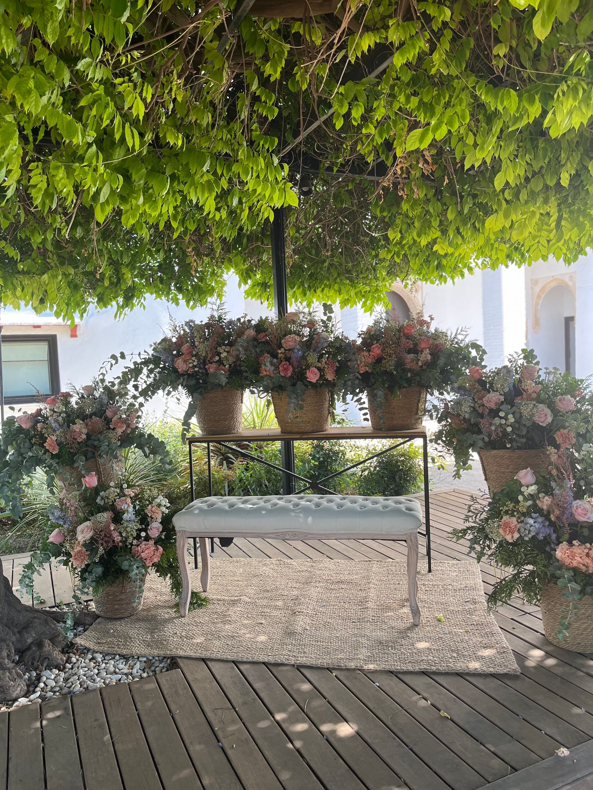 Una mesa con flores debajo de un árbol.