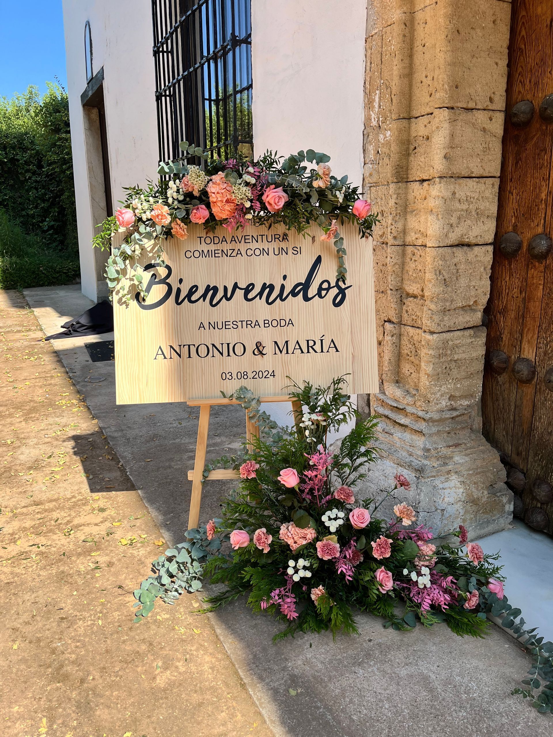 Un cartel de madera con flores está frente a un edificio.