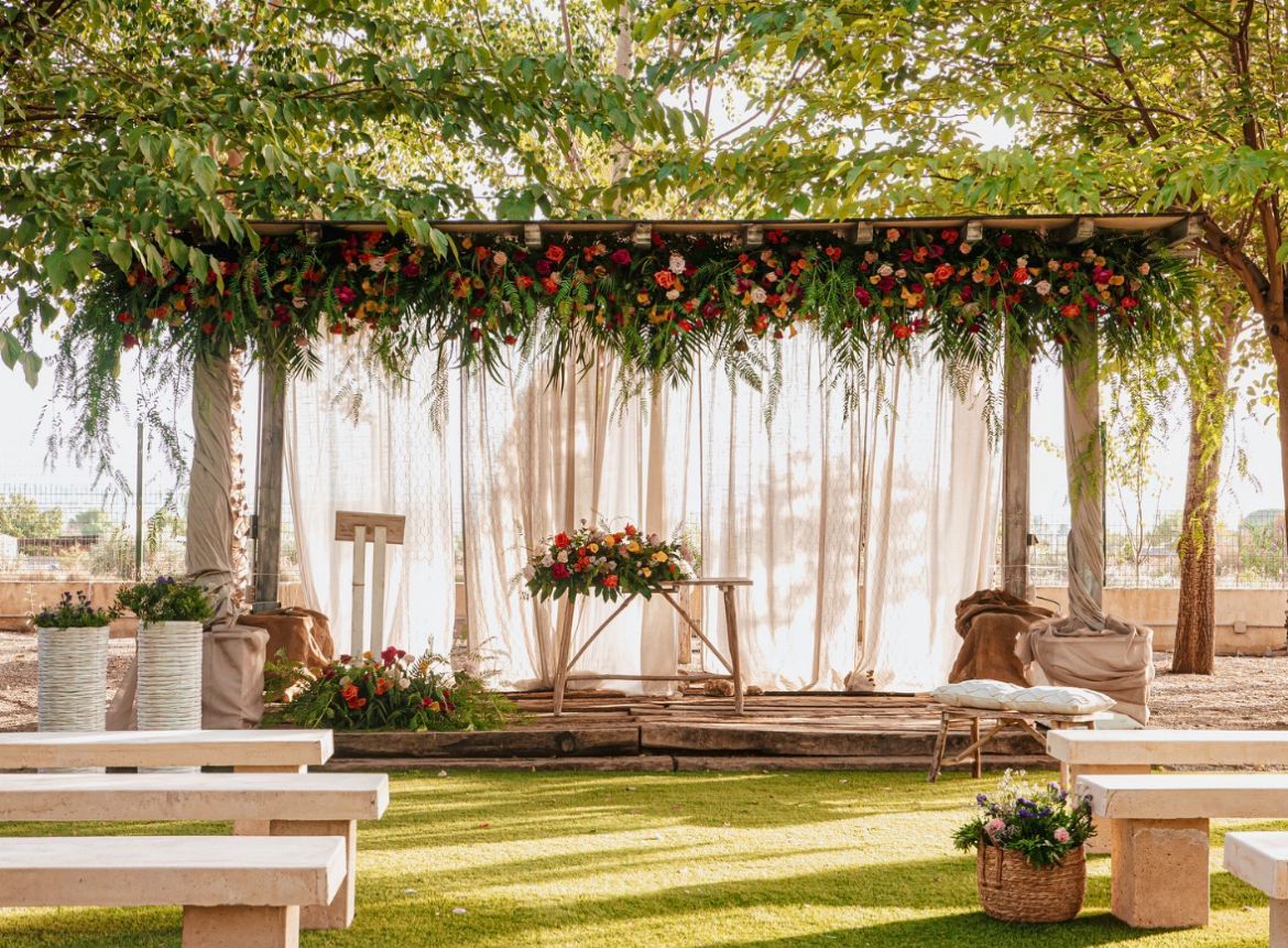 Se lleva a cabo una ceremonia de boda bajo un dosel con flores colgando del techo.