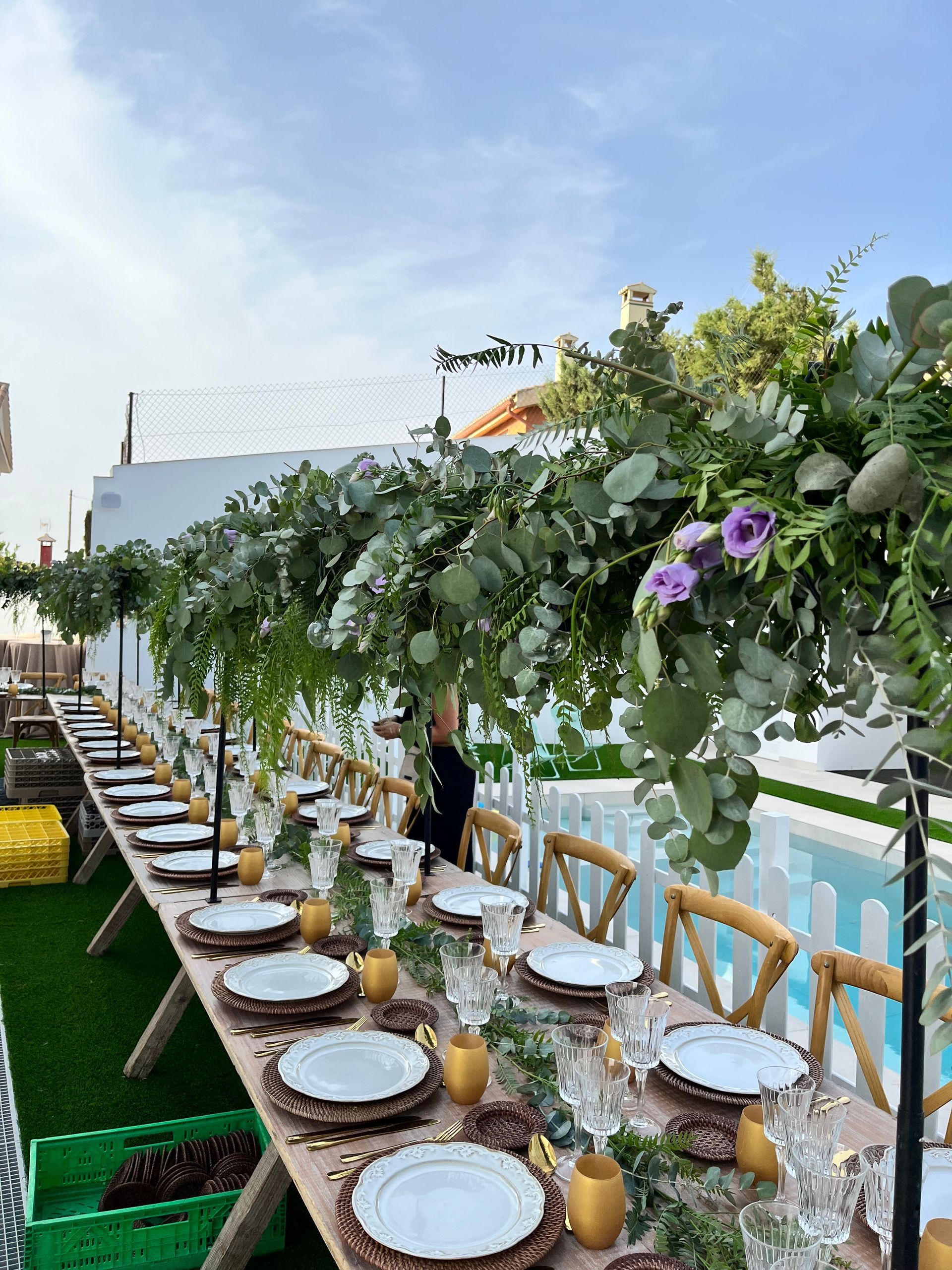 Una mesa larga con platos, vasos y flores sobre ella.