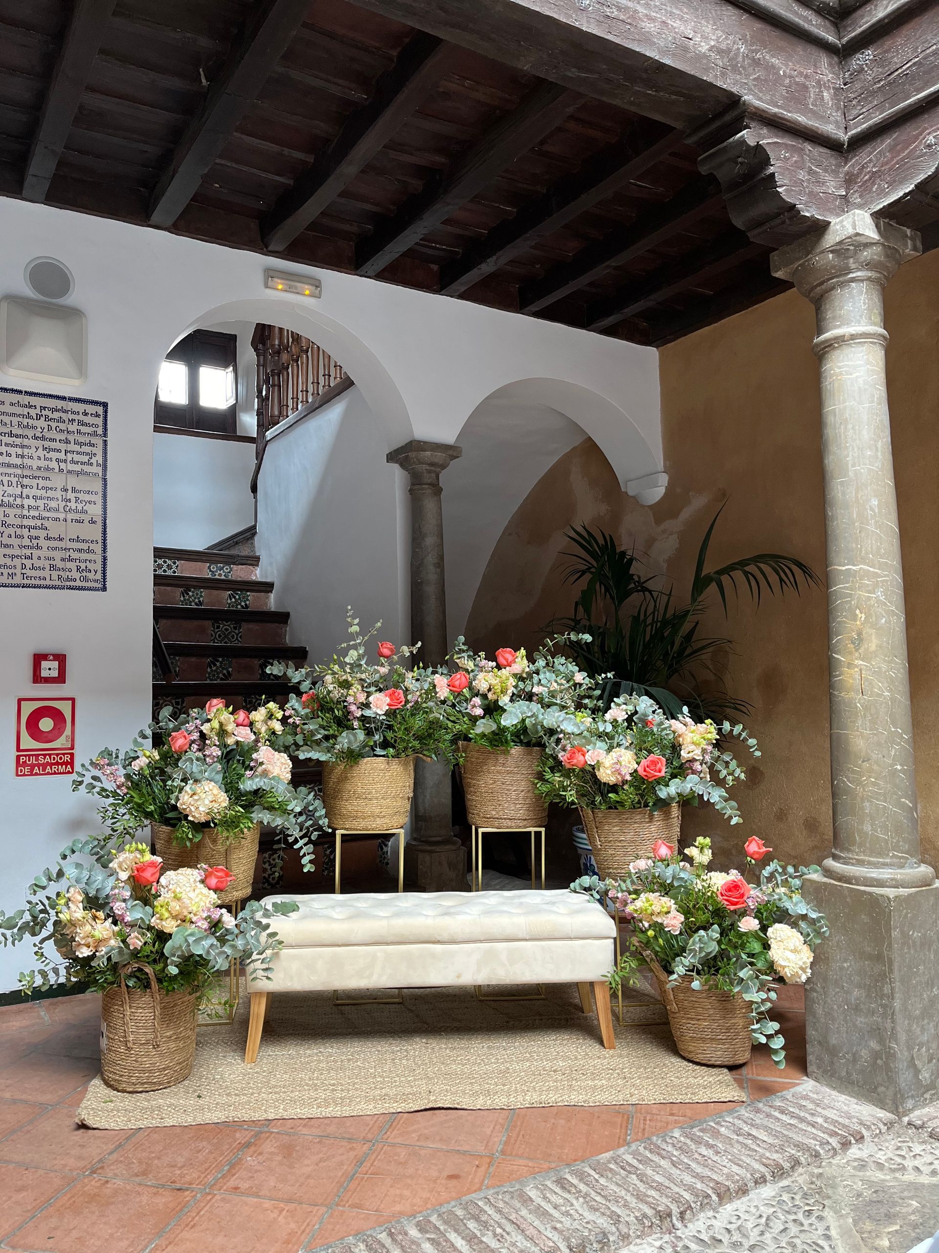 Una habitación con un banco y cestas de flores.