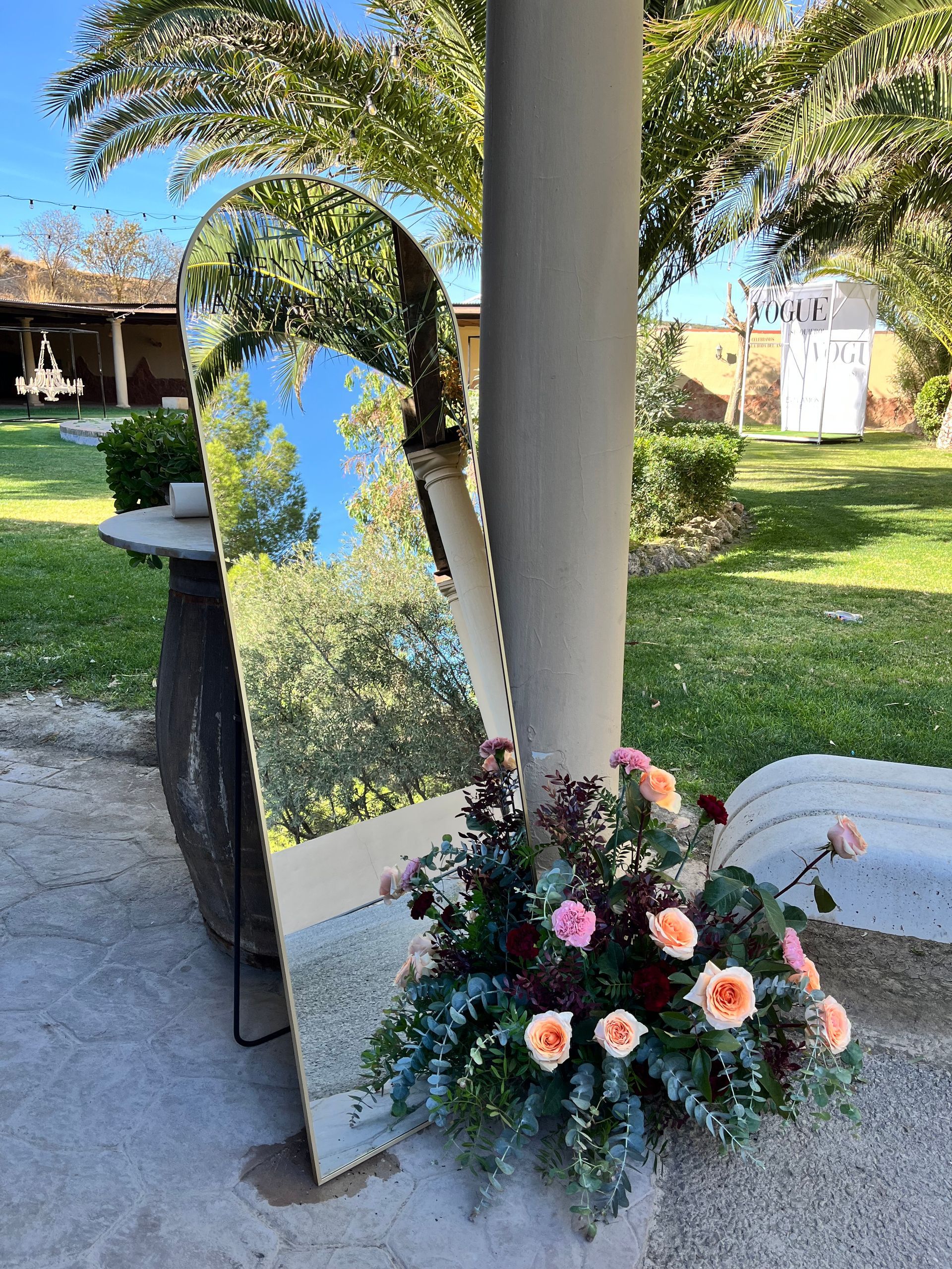 Un gran espejo está al lado de un jarrón con flores.