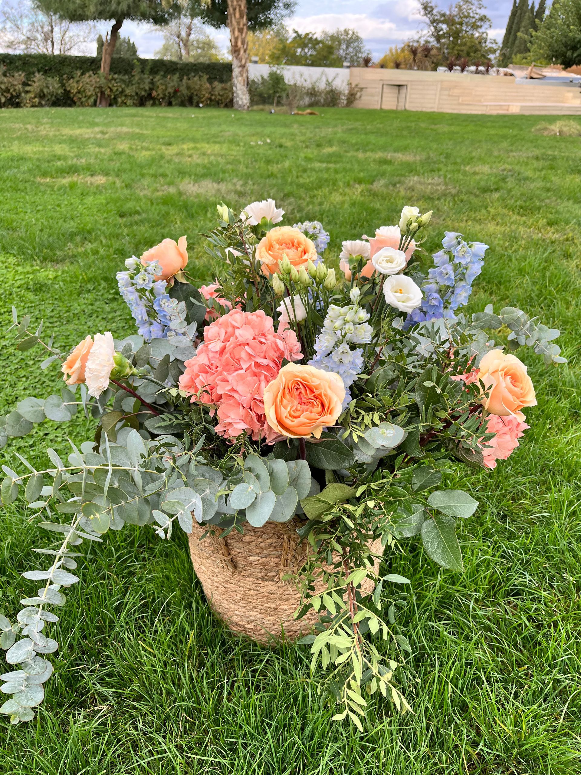 Una canasta llena de flores se encuentra sobre un exuberante campo verde.