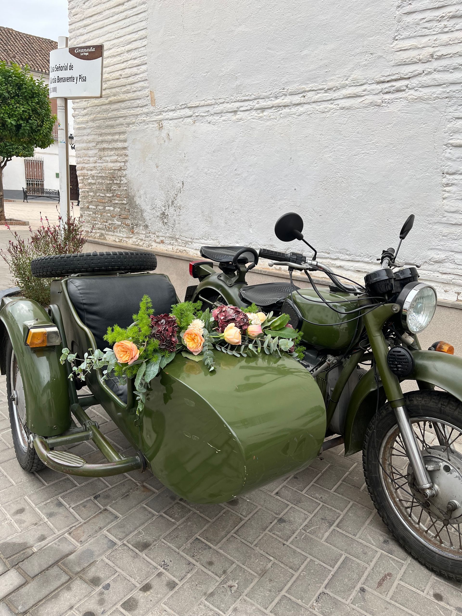Una motocicleta con sidecar decorada con flores está estacionada al costado de la carretera.
