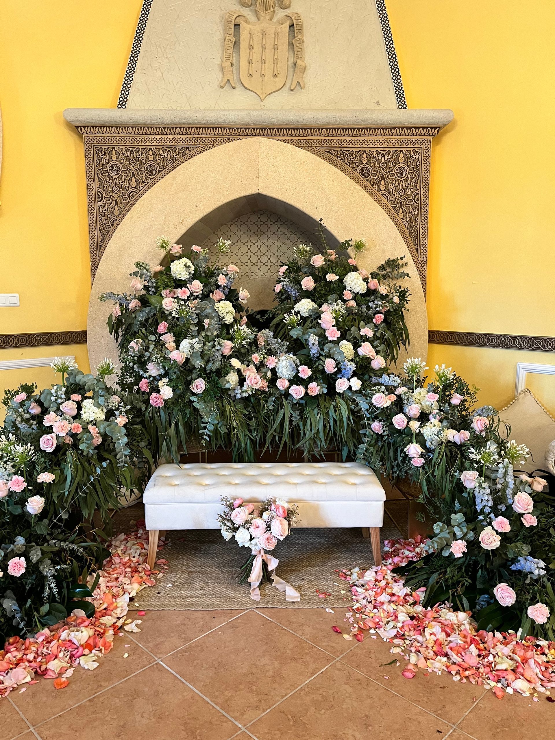 Una chimenea está decorada con flores y pétalos para una ceremonia de boda.