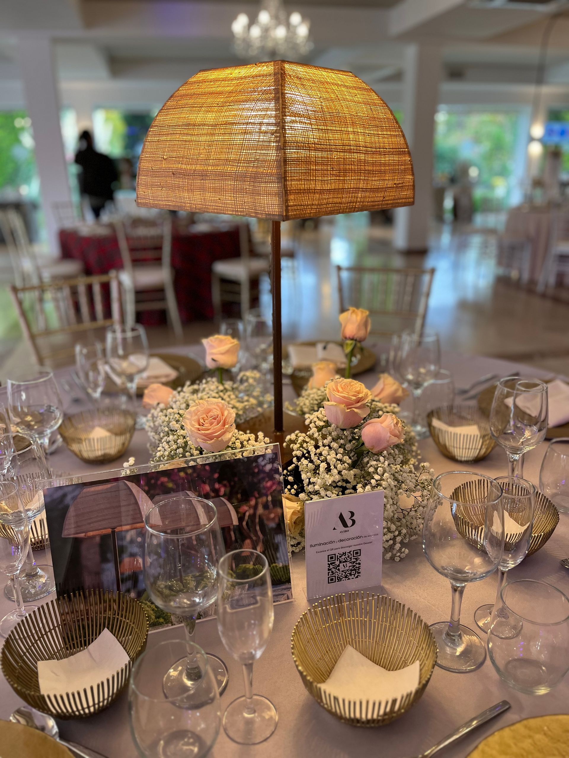 Una mesa preparada para una recepción de boda con una lámpara y flores sobre ella.