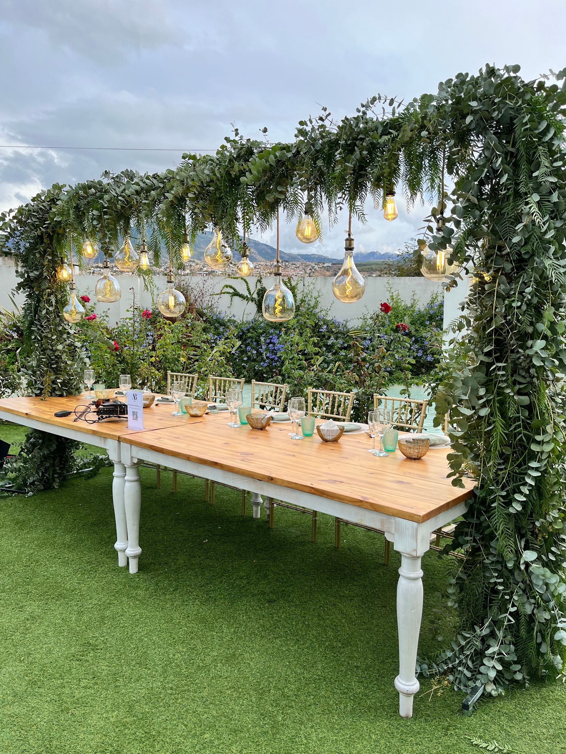 Una larga mesa de madera se encuentra sobre un exuberante campo verde.