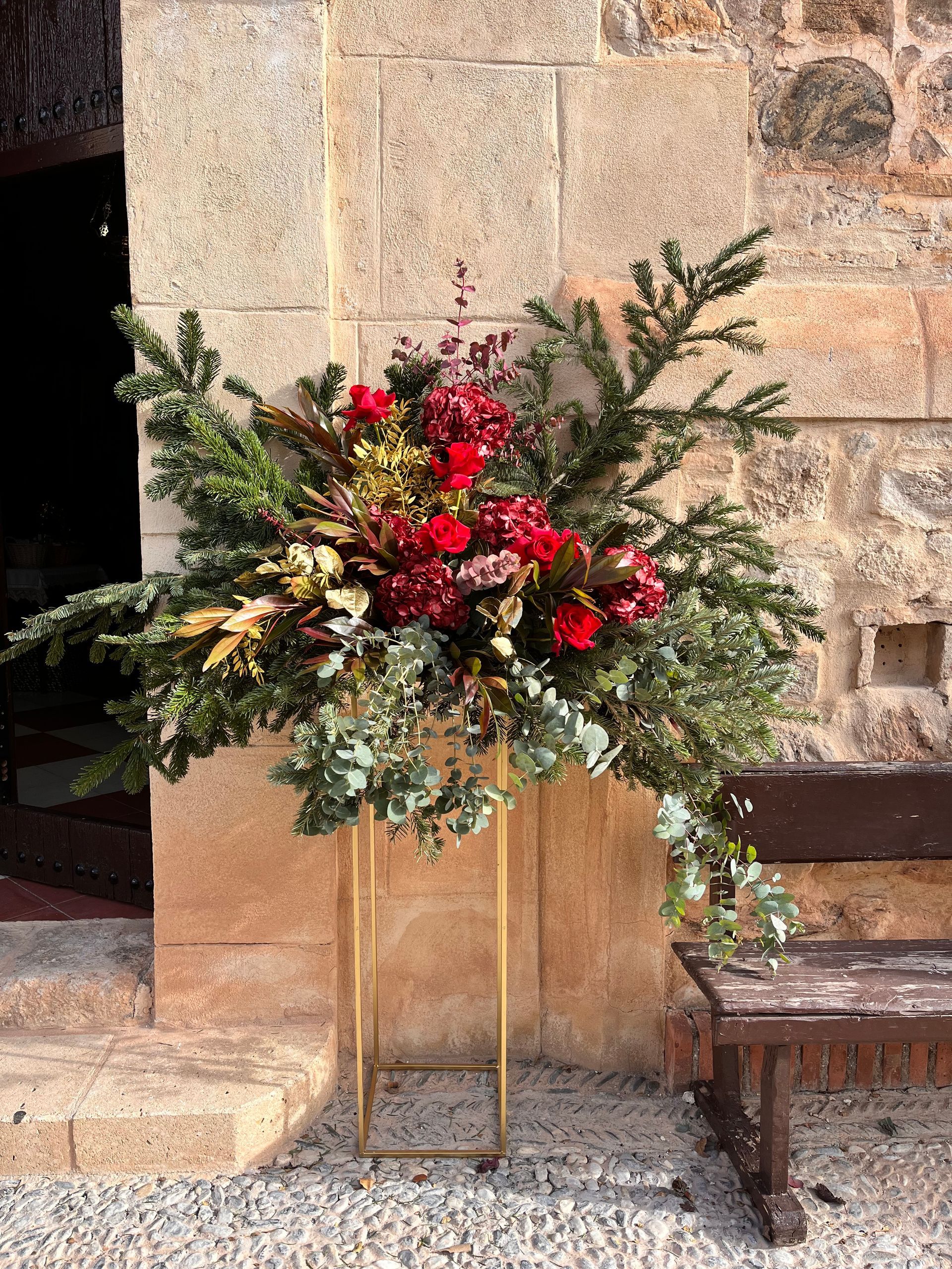 Un gran jarrón lleno de flores se encuentra frente a un edificio de piedra.